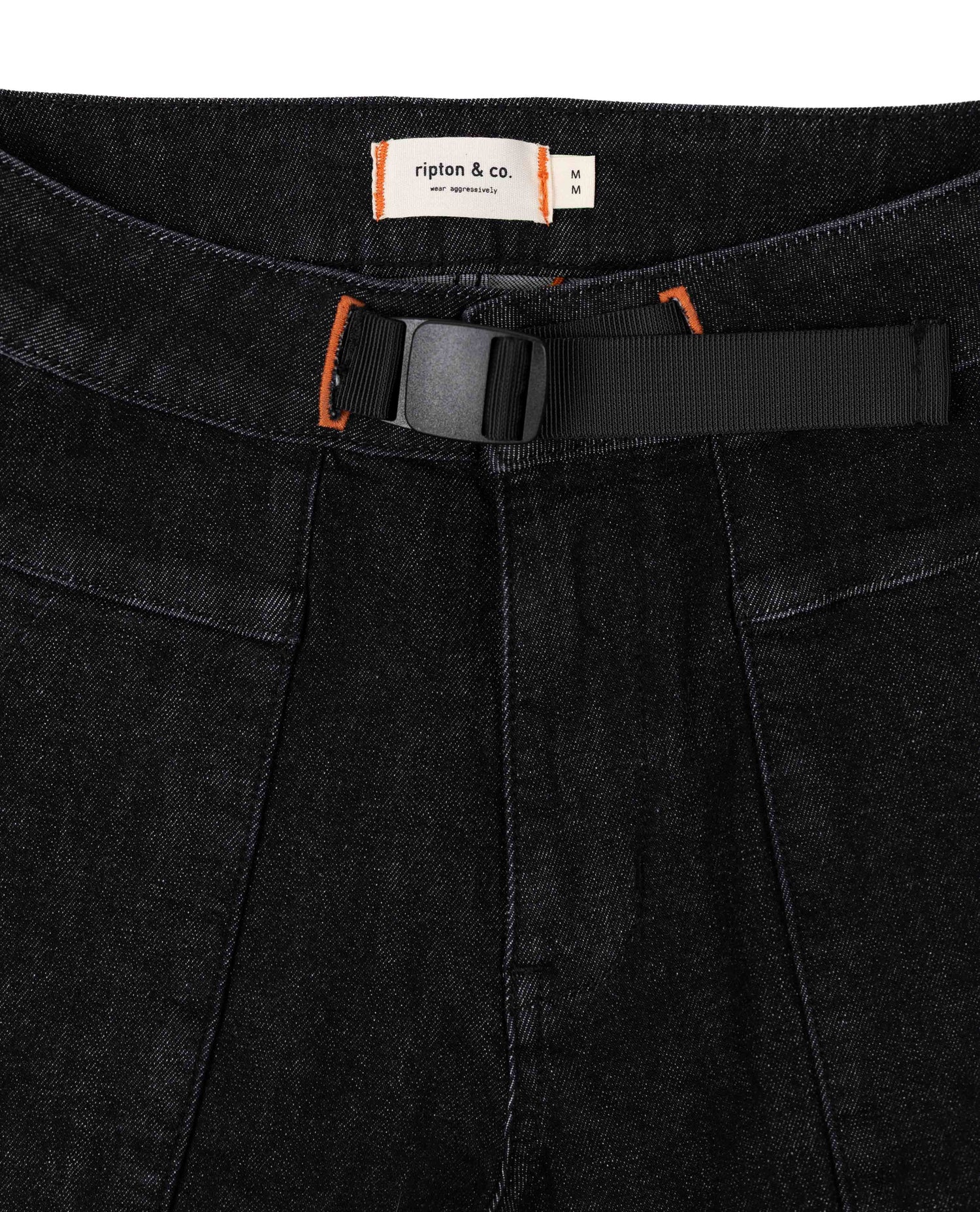 Close-up of black pants with a belt and visible brand label on a black background