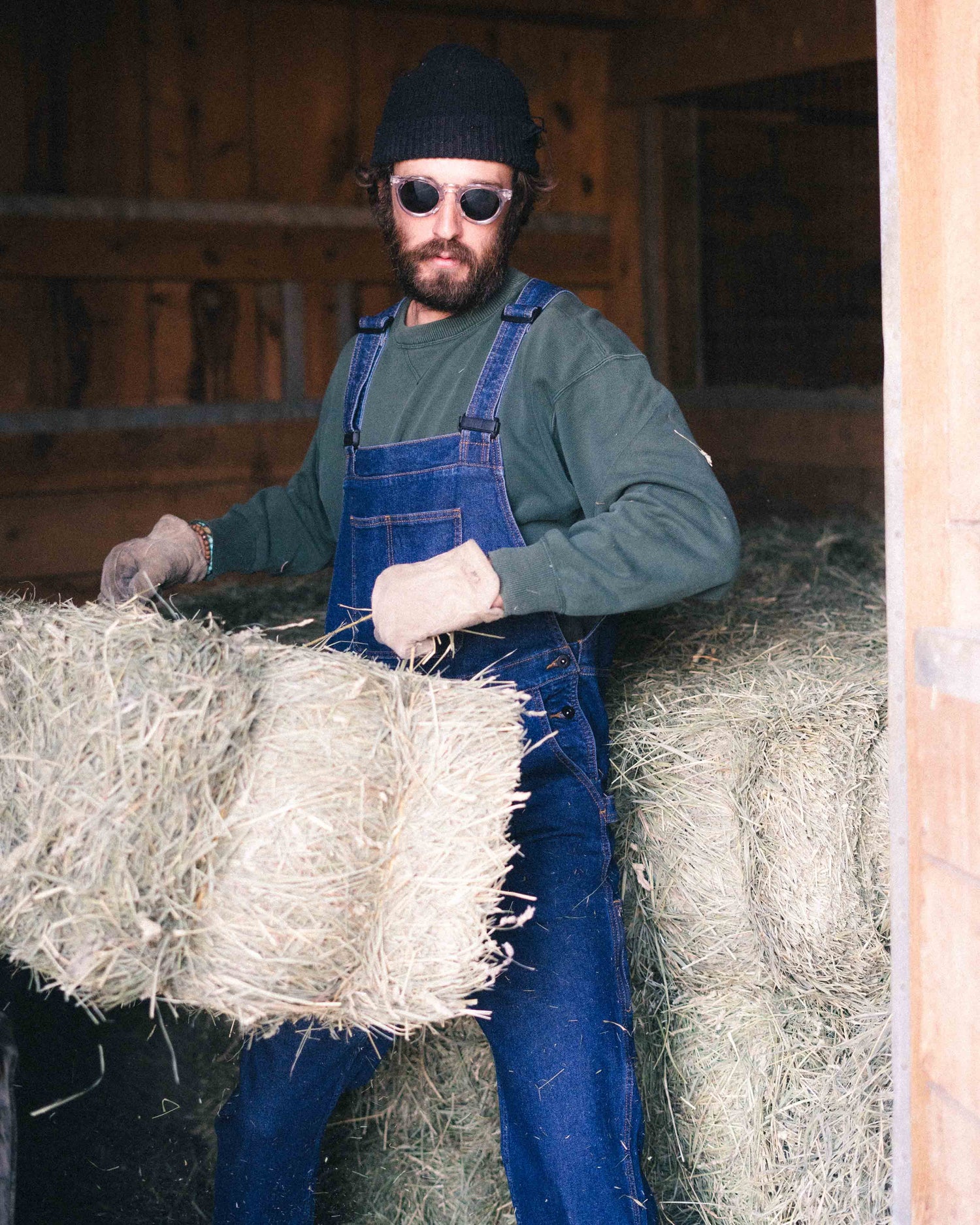 Guy chucking hay bales wearing overalls