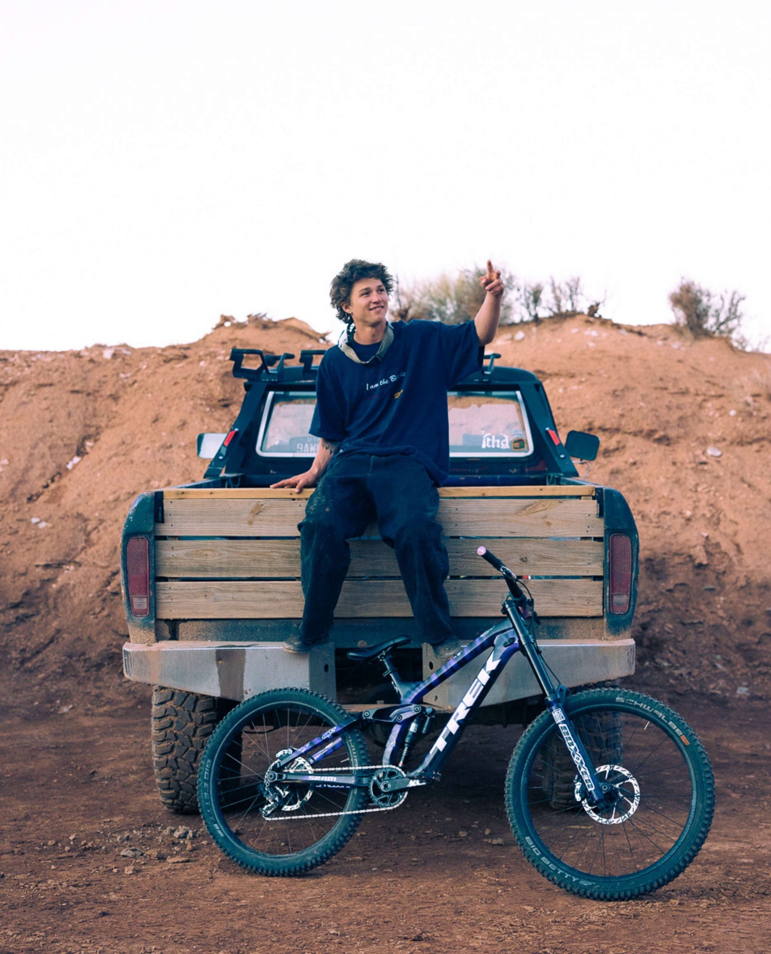 Person sitting on a truck bed with a bicycle in front, outdoors.