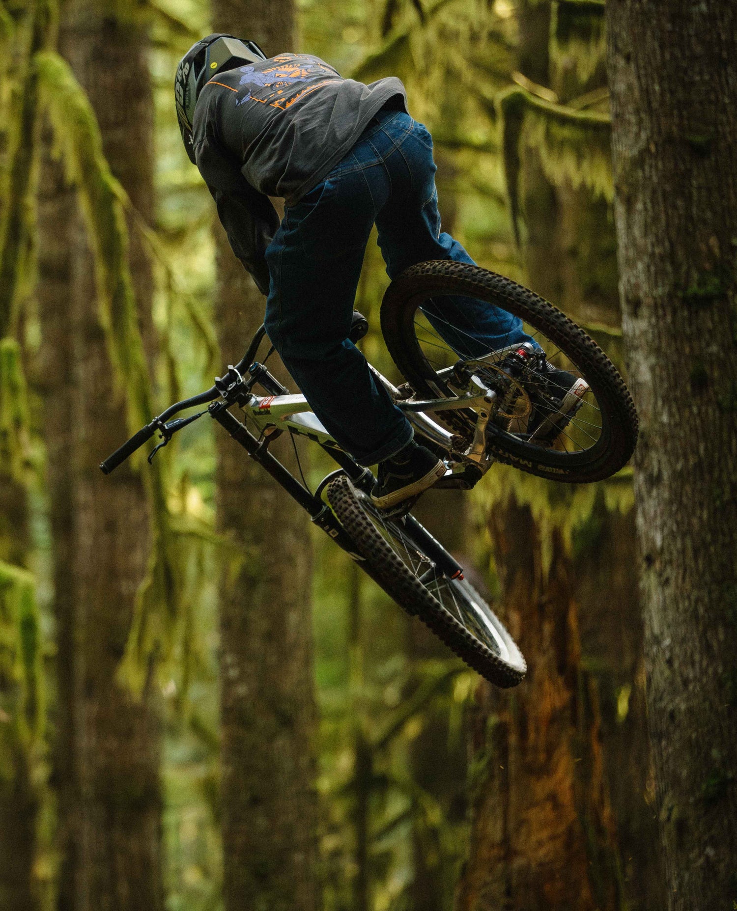 Person on a mountain bike in mid-air against a forest background