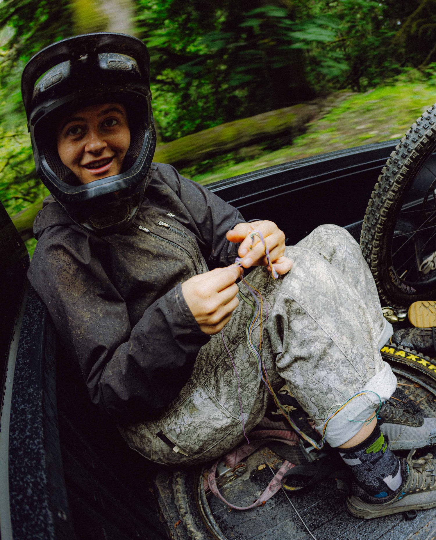 Person wearing a helmet and protective gear, sitting on a vehicle with a forest background