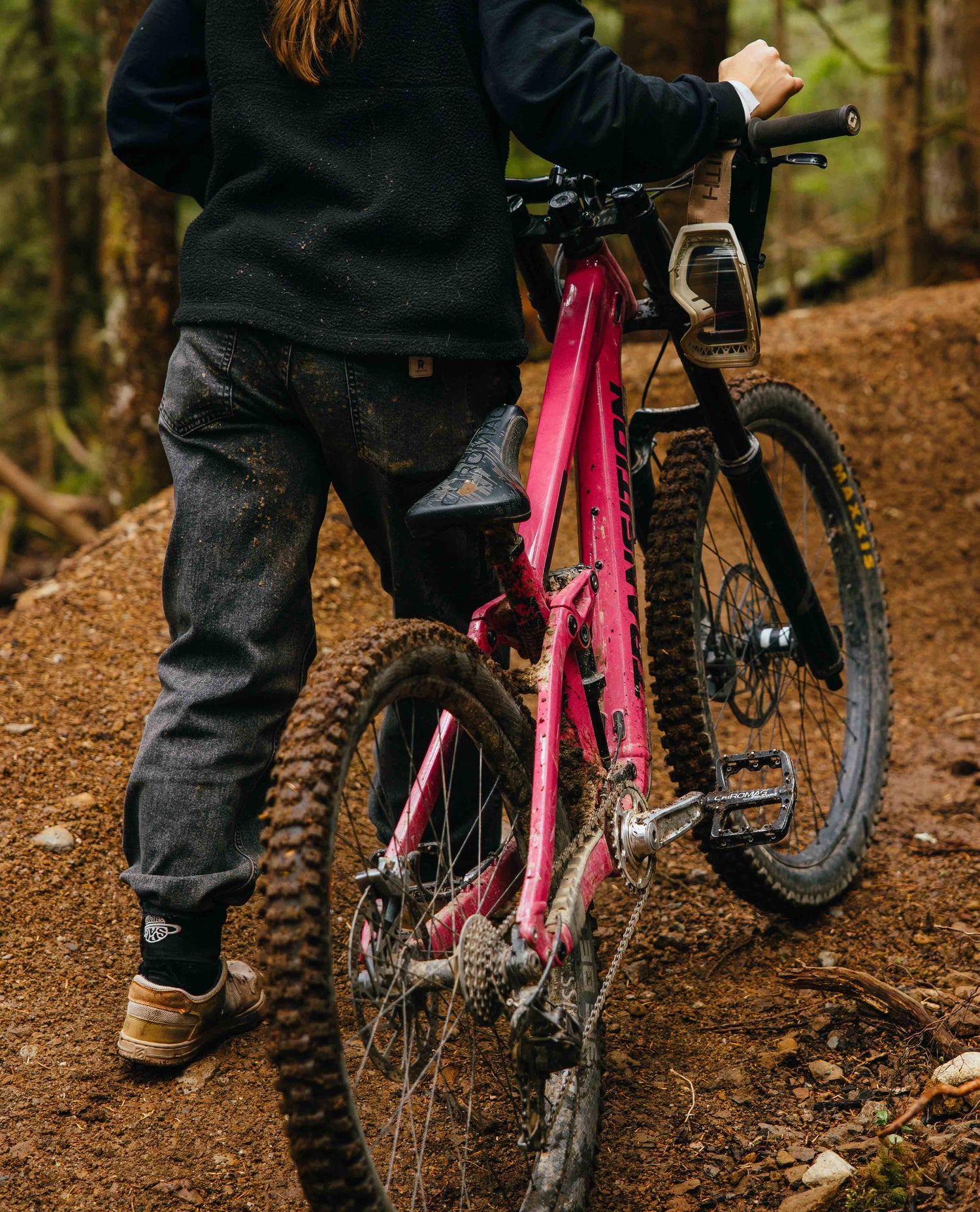 Person with a pink bicycle on a muddy trail in a forest