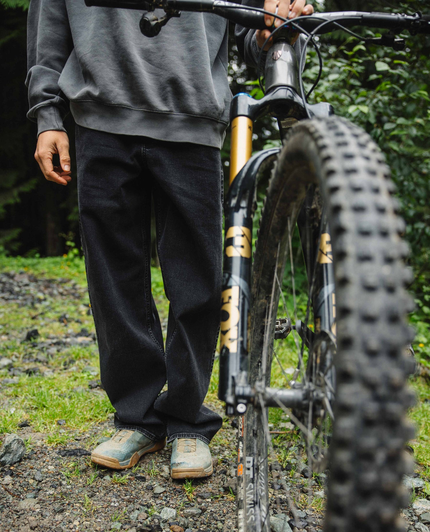 Person standing next to a mountain bike on a trail