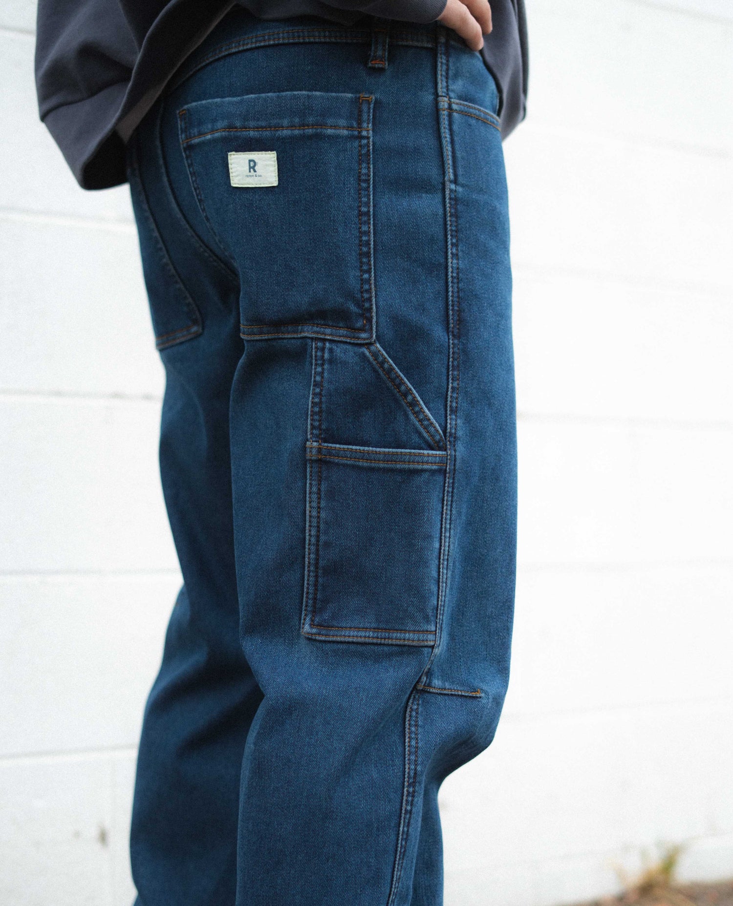 Blue jeans with a brand logo on the back pocket against a white background