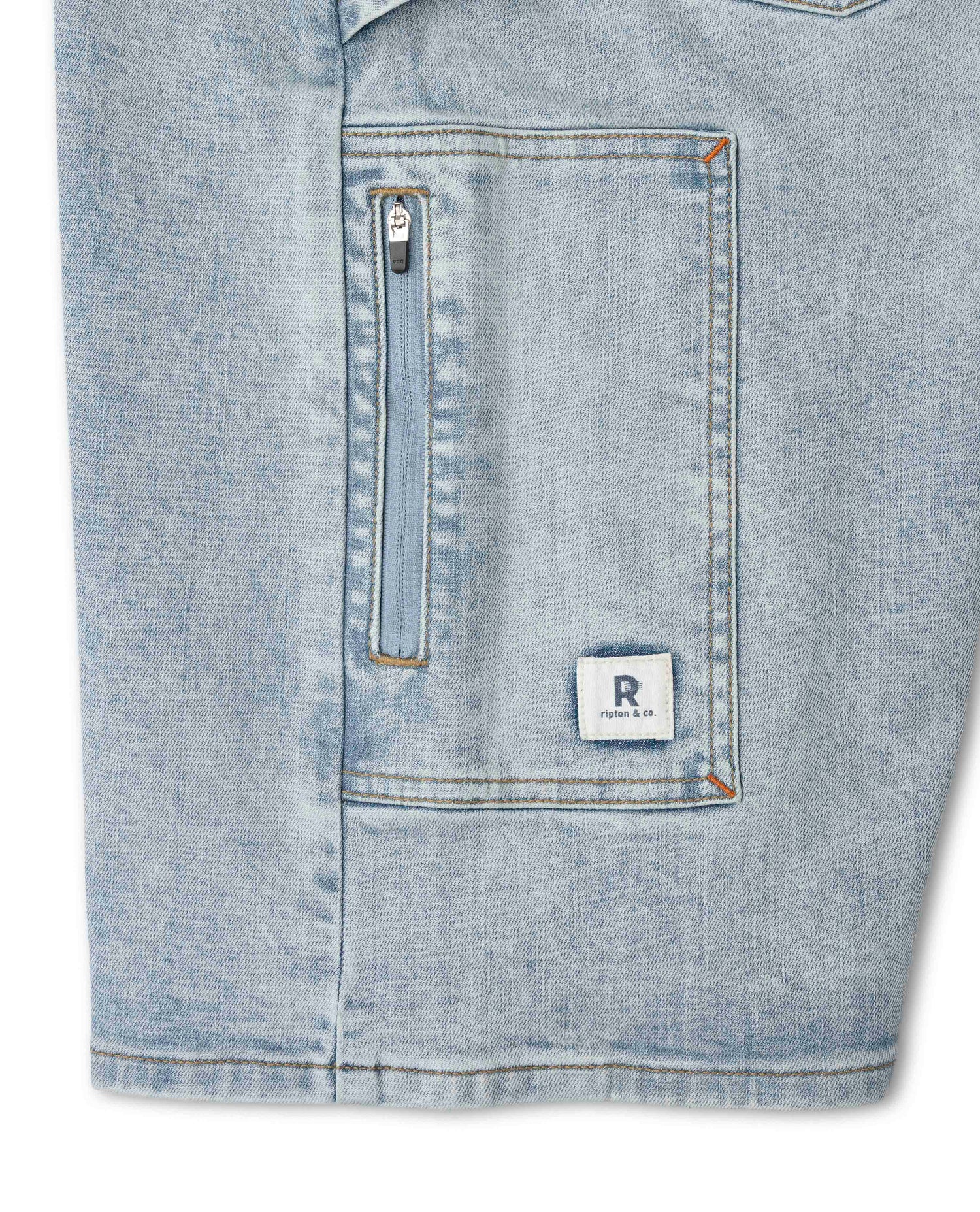 Close-up of a blue denim jacket with a zipper and brand logo on a white background