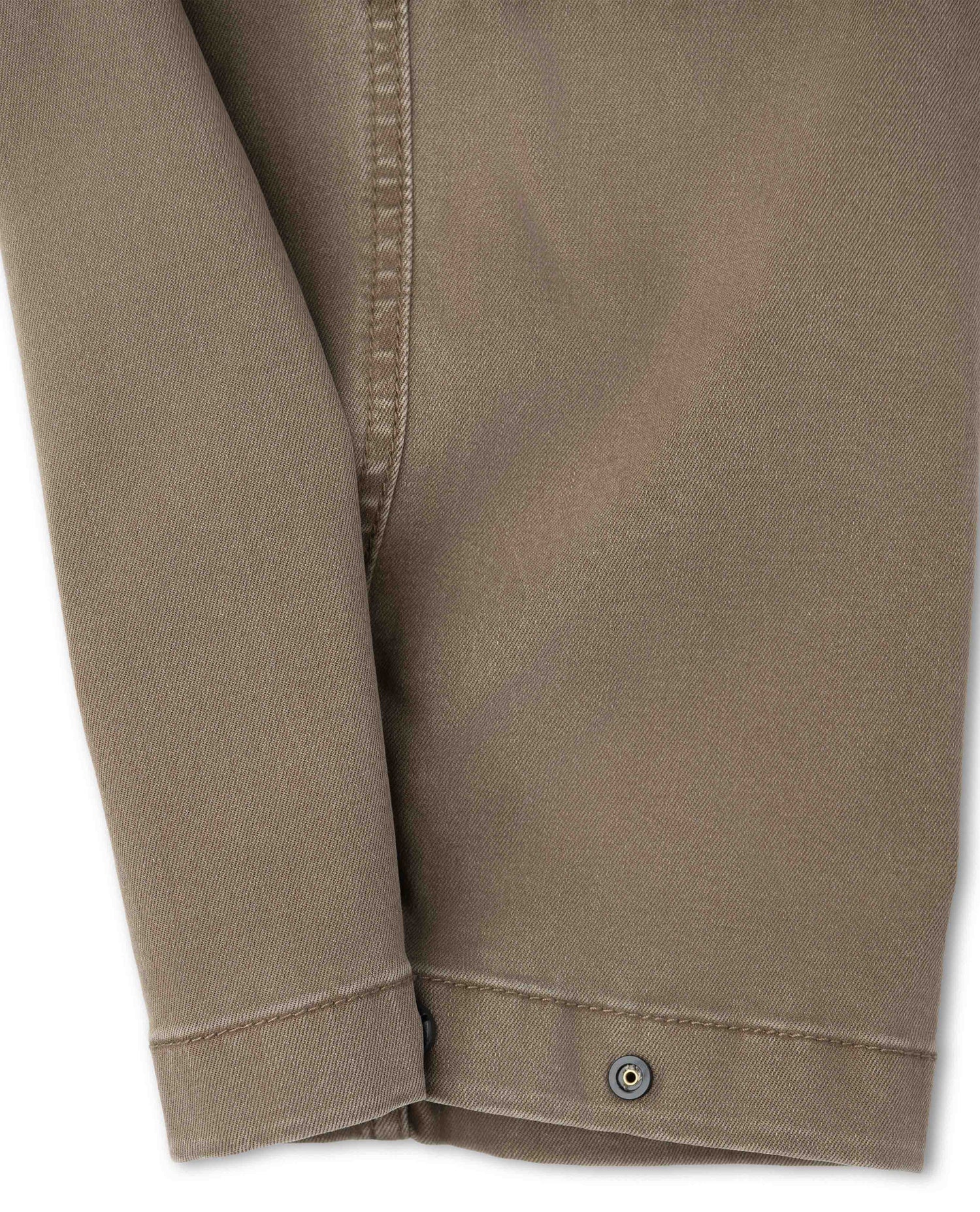 Close up of snap closure on brown pants with white background