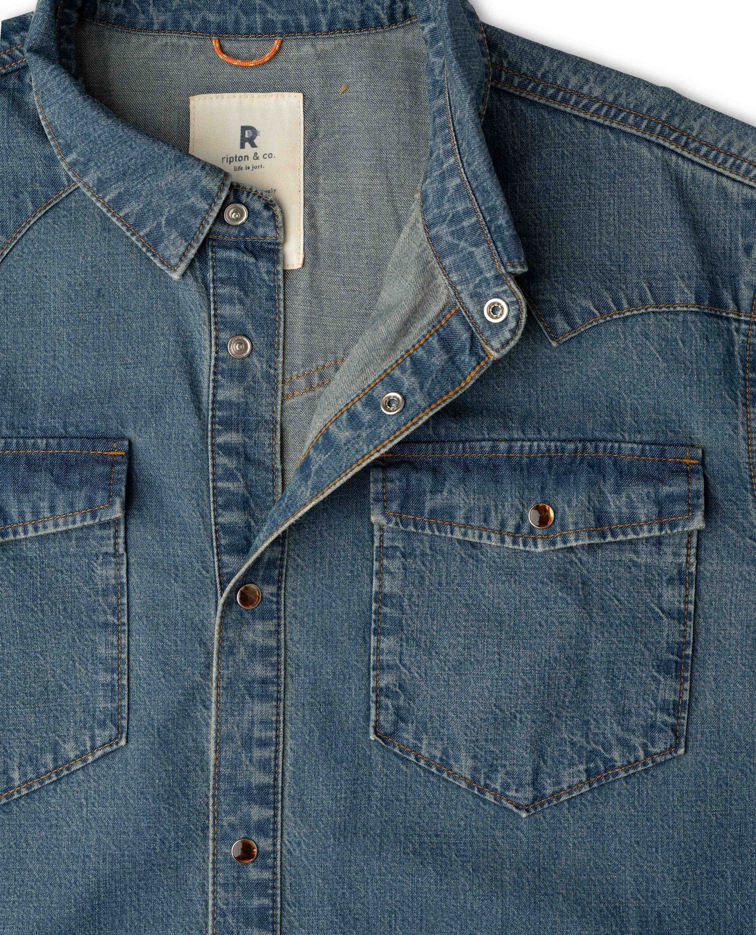 Close-up of a blue denim button-up shirt with two chest pockets.