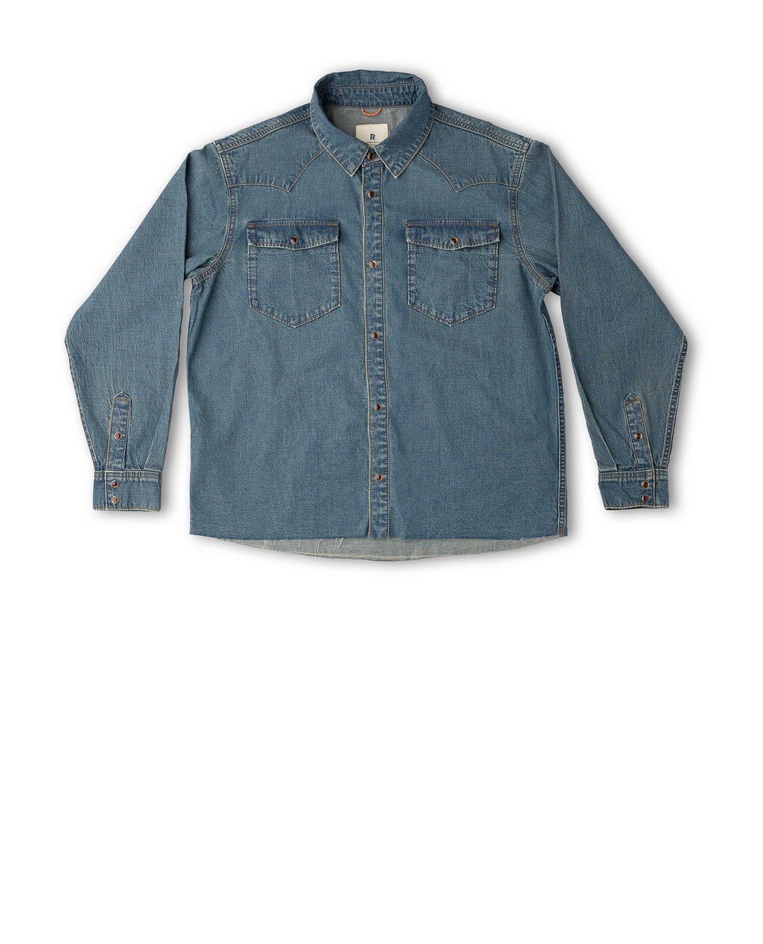 A medium-wash blue denim long-sleeve button-up shirt with two chest flap pockets, laid flat against a white background.
