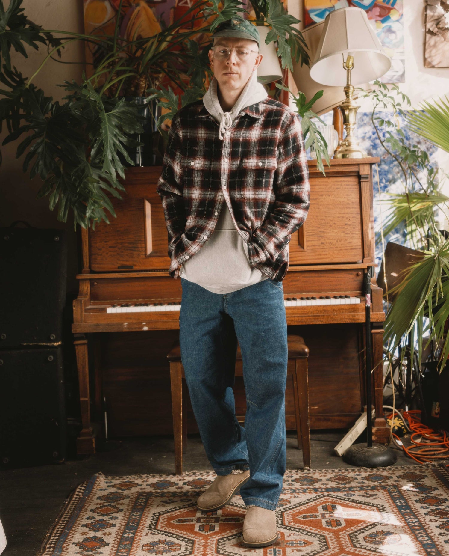 Man standing in a room with plants and a piano