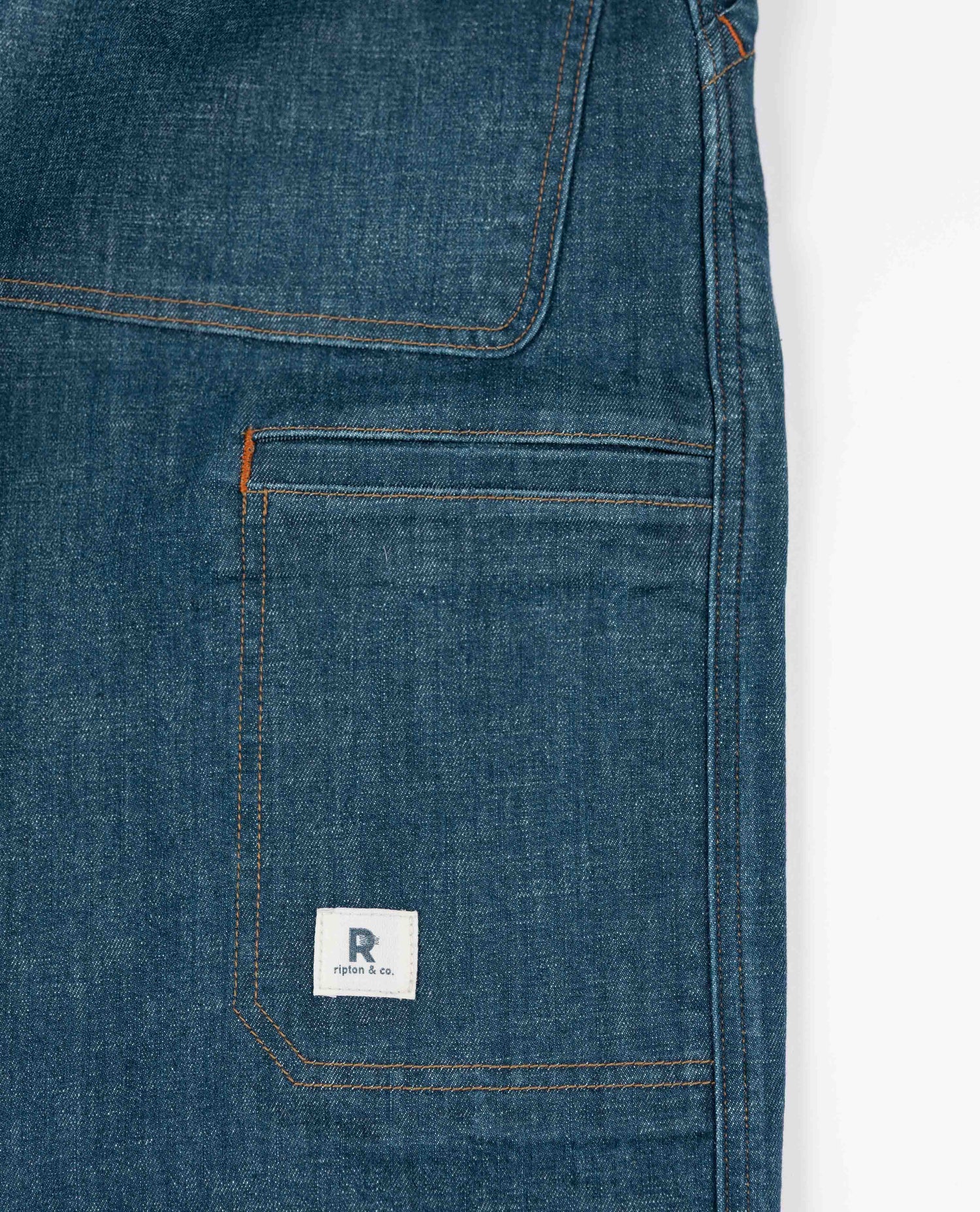 Close-up of blue denim pocket with a brand logo on a white background