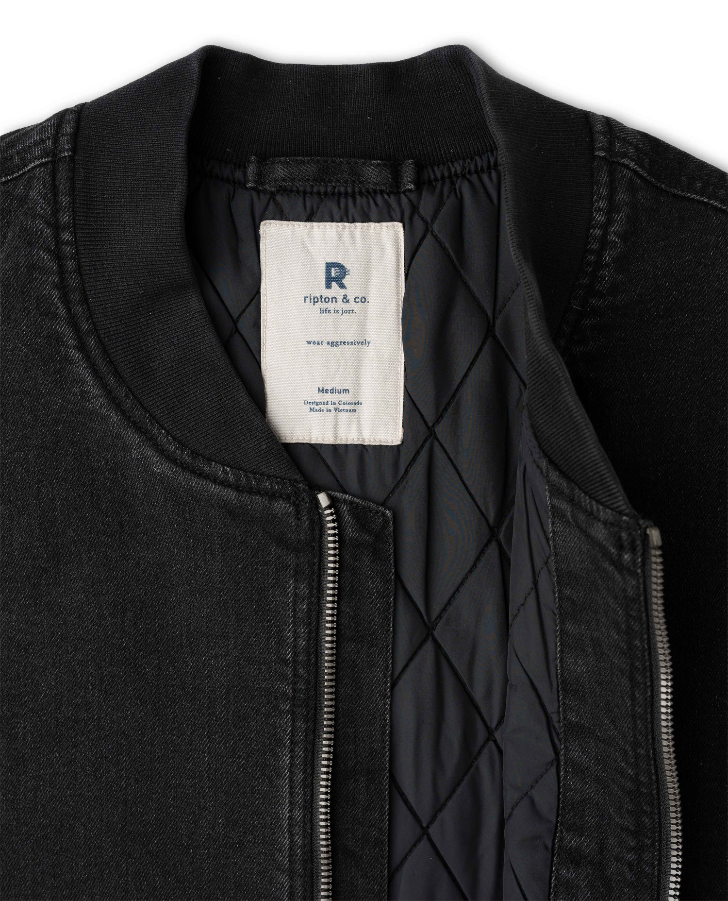 Close-up of a black bomber jacket with a quilted black interior lining and a white brand label reading 'Ripton & co.'