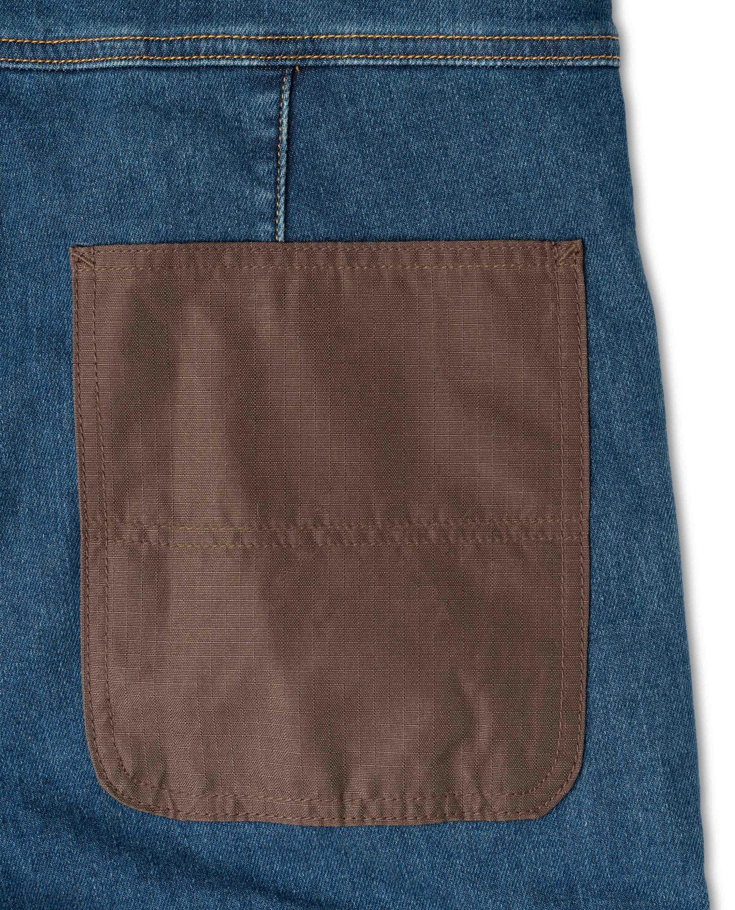 Close-up of a blue denim pocket with a brown patch on a white background