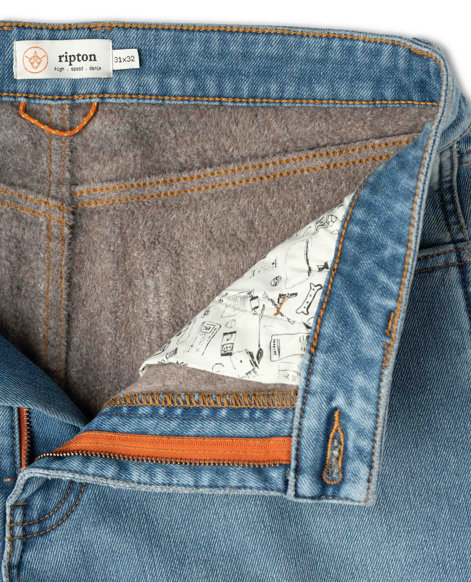 Close-up of a blue denim fabric with a patterned lining and orange stitching, featuring the Ripton brand label.