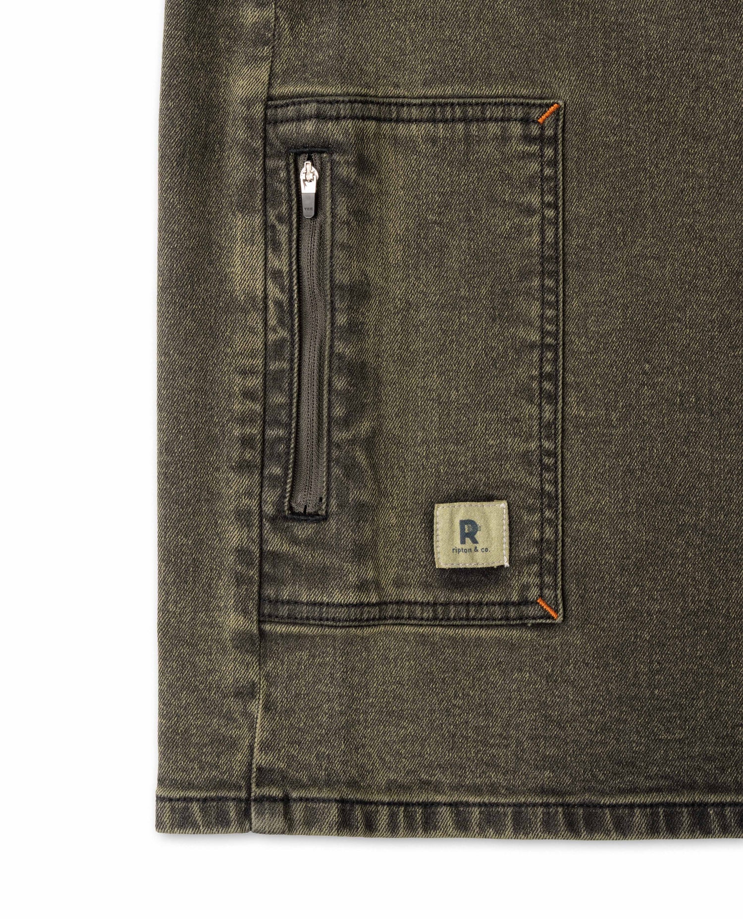 Close-up of a pocket on a dark denim jacket with a brand logo.