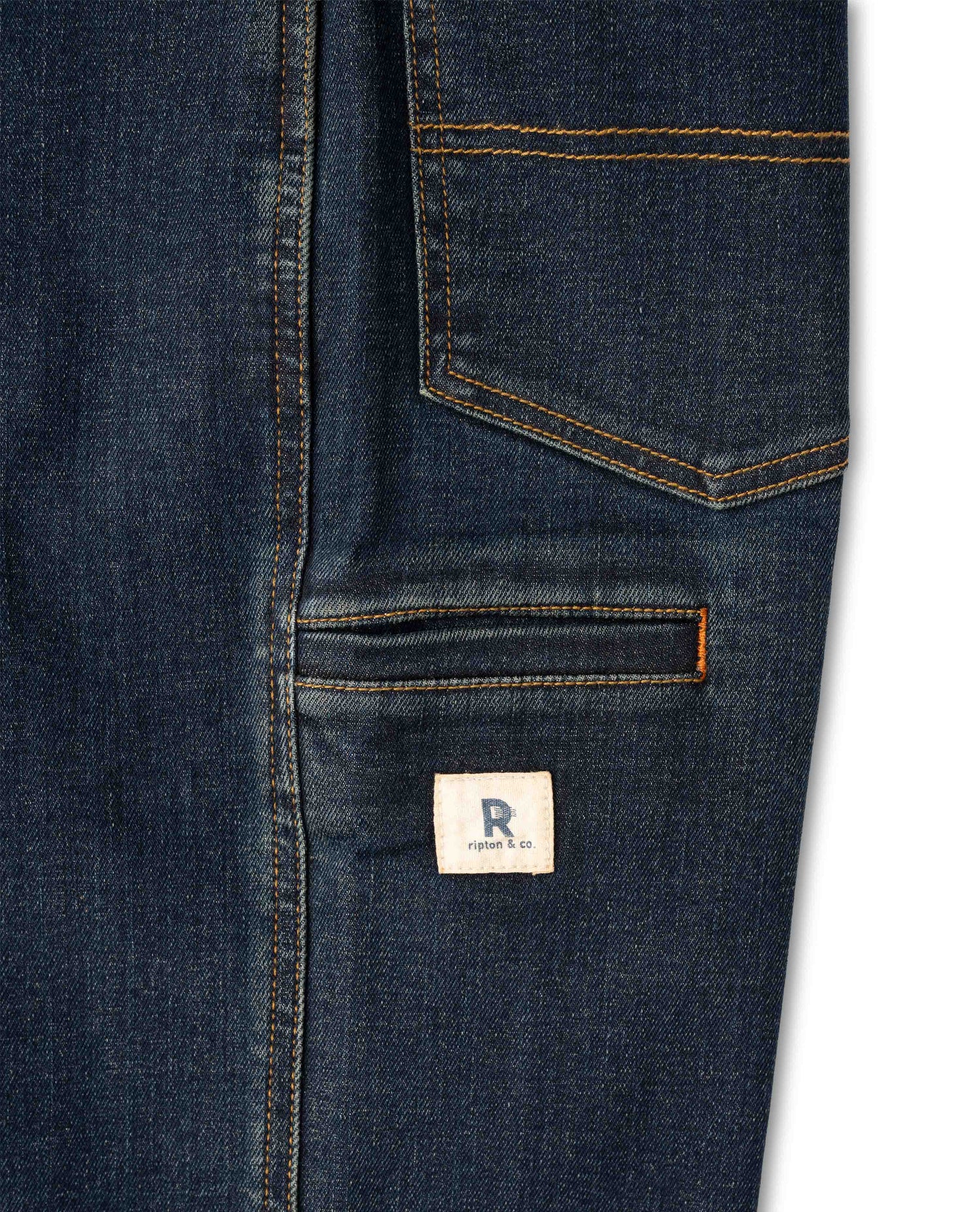 Close-up of a dark blue denim jacket with a brand label on a white background