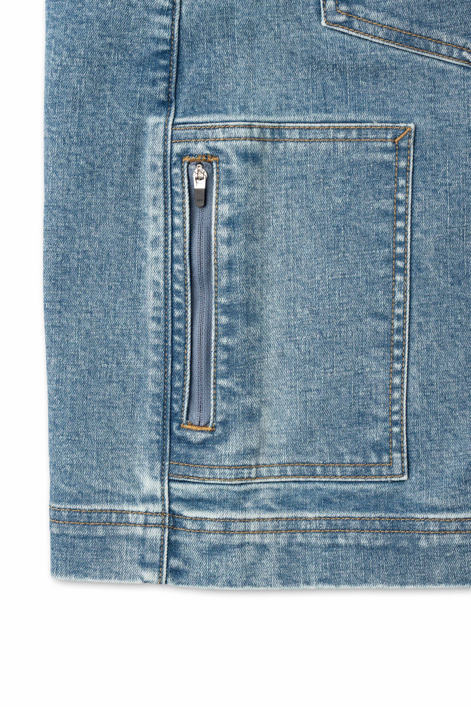 Close-up of a blue denim jacket with a zipper pocket on a white background