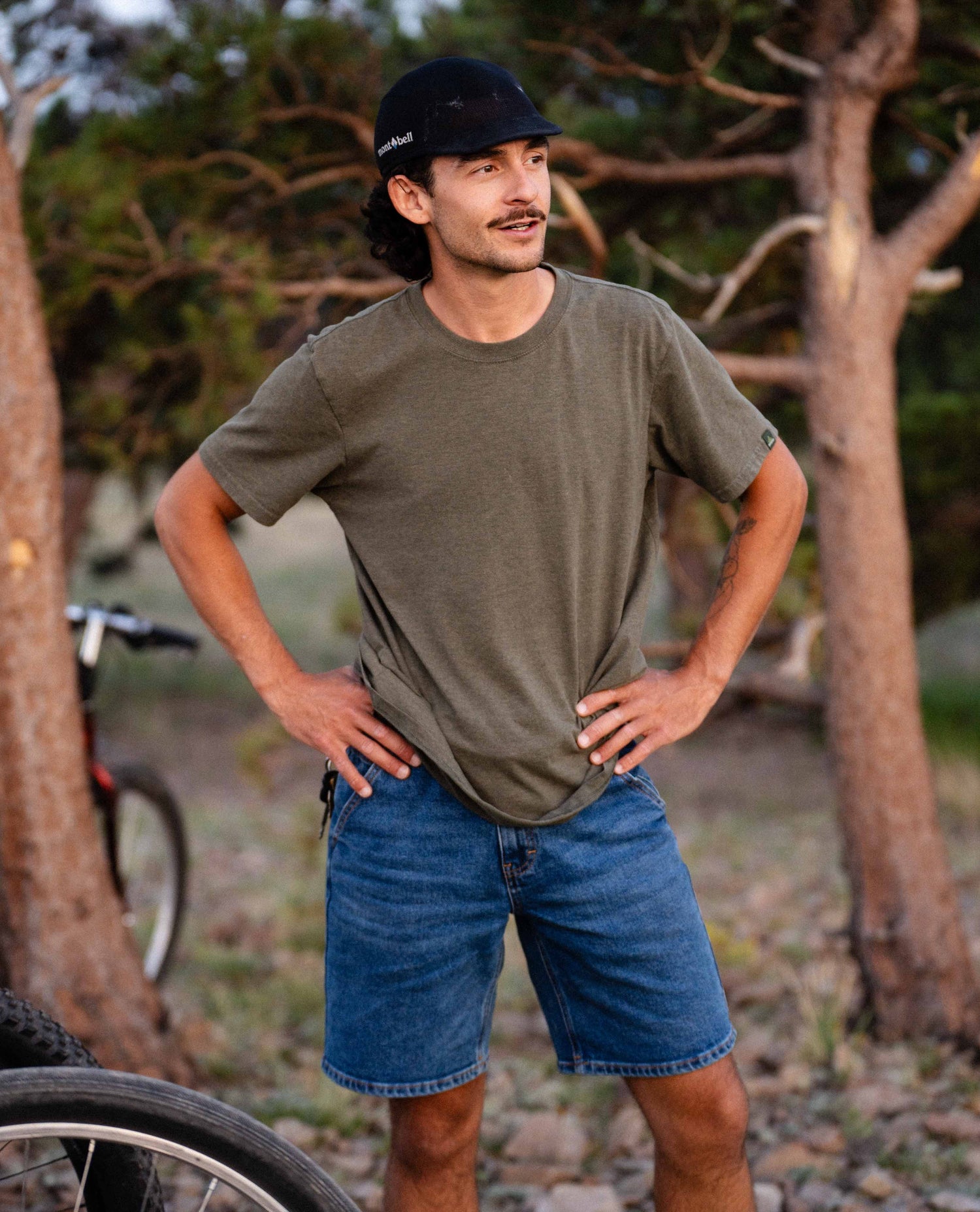 Man standing in Ripton DTJ jorts in the woods. 