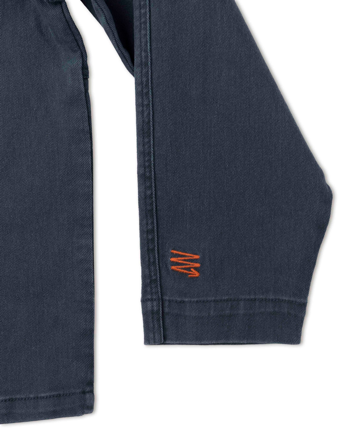 An up close image showcasing the Ripton "Rip" logo in orange on the sleeve of a Ripton Sport Utility Jacket in navy.