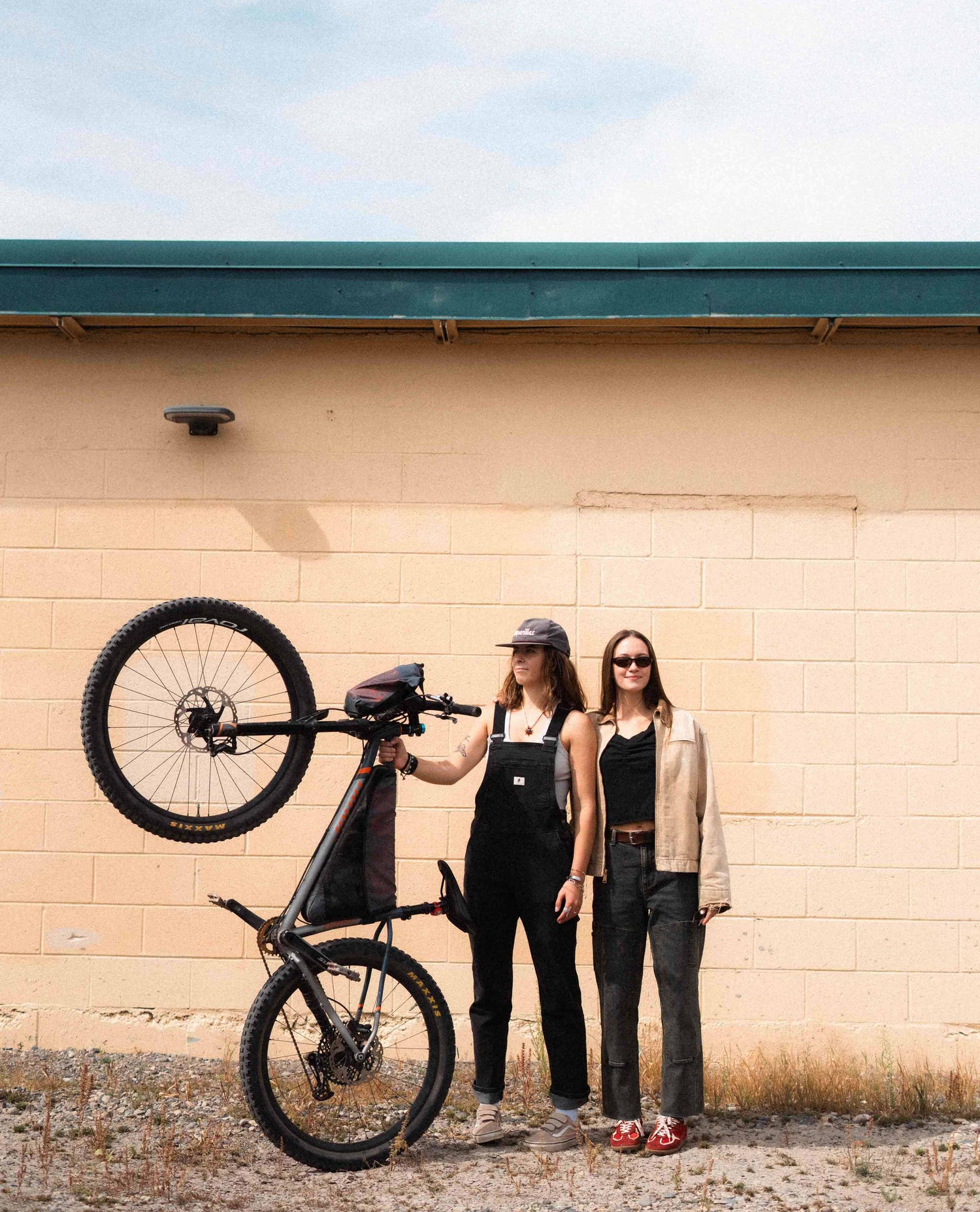 Two women standing against a wall. 