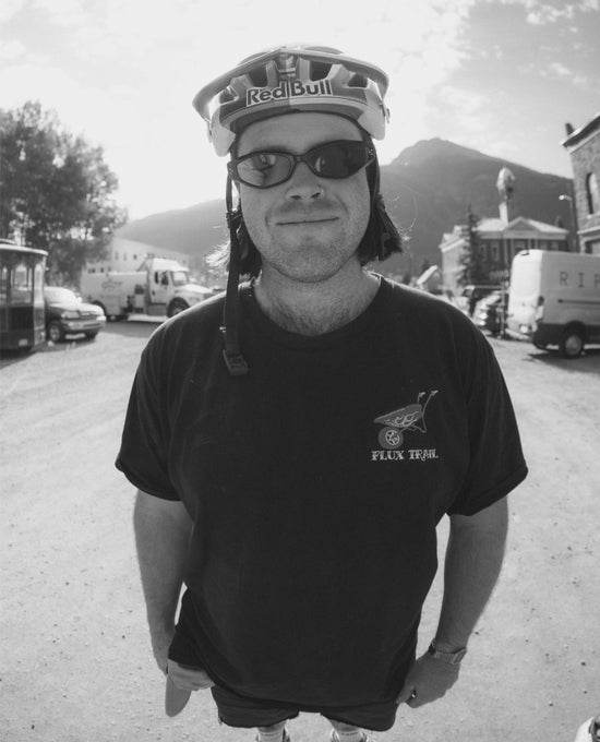 Remy Morton wearing a black t-shirt with a logo and a helmet with a 'Red Bull' logo, standing outdoors.