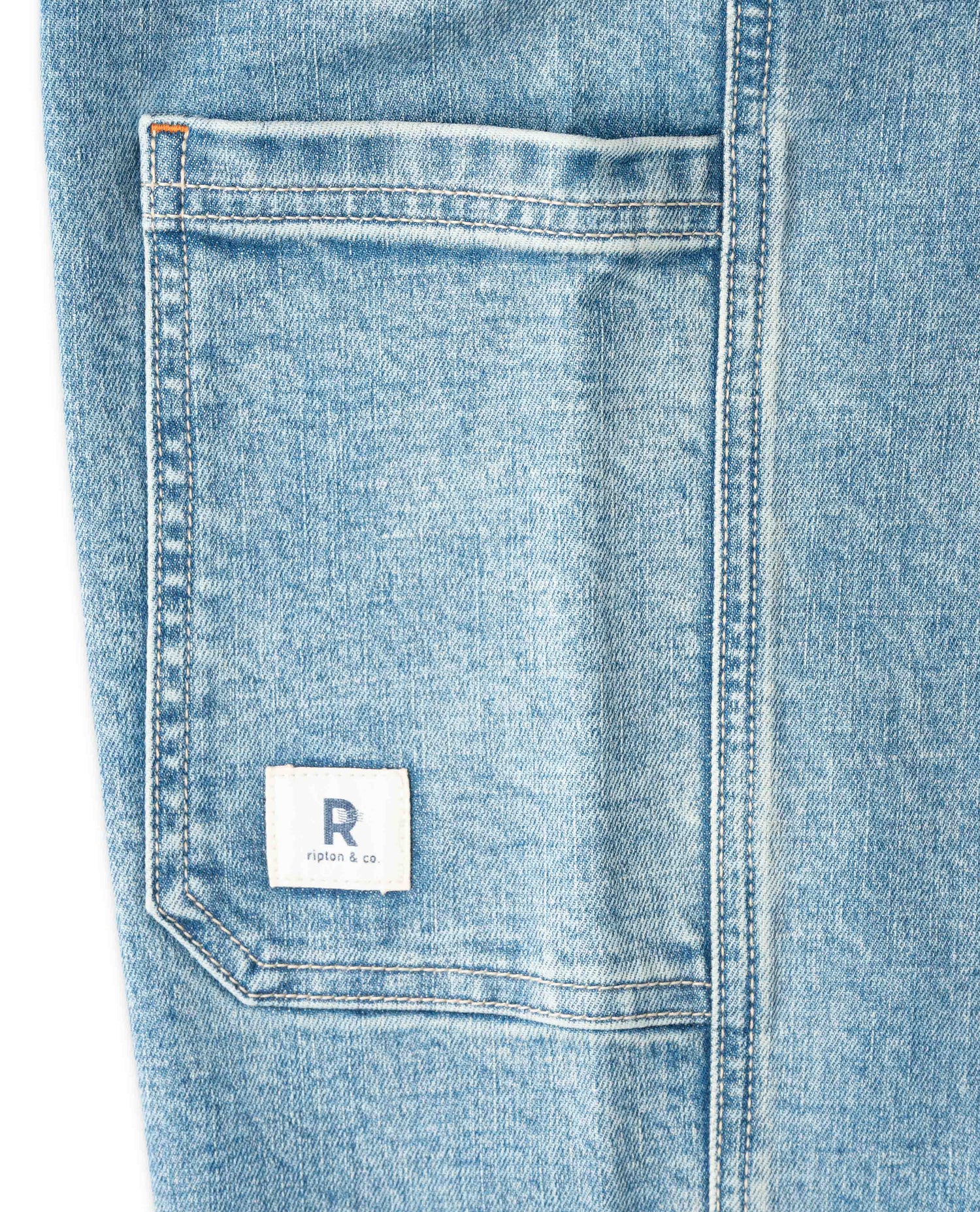 Close-up of a blue denim pocket with a brand label on a white background