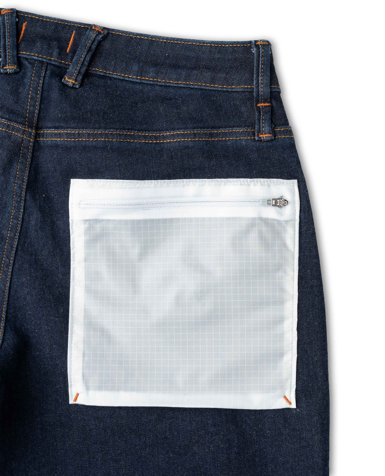 Close-up of dark blue jeans with a white pocket on a light gray background