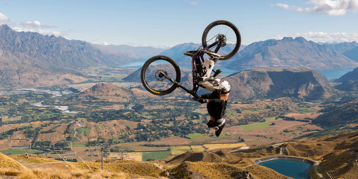 Person on a bicycle performing a trick with mountains and valley in the background