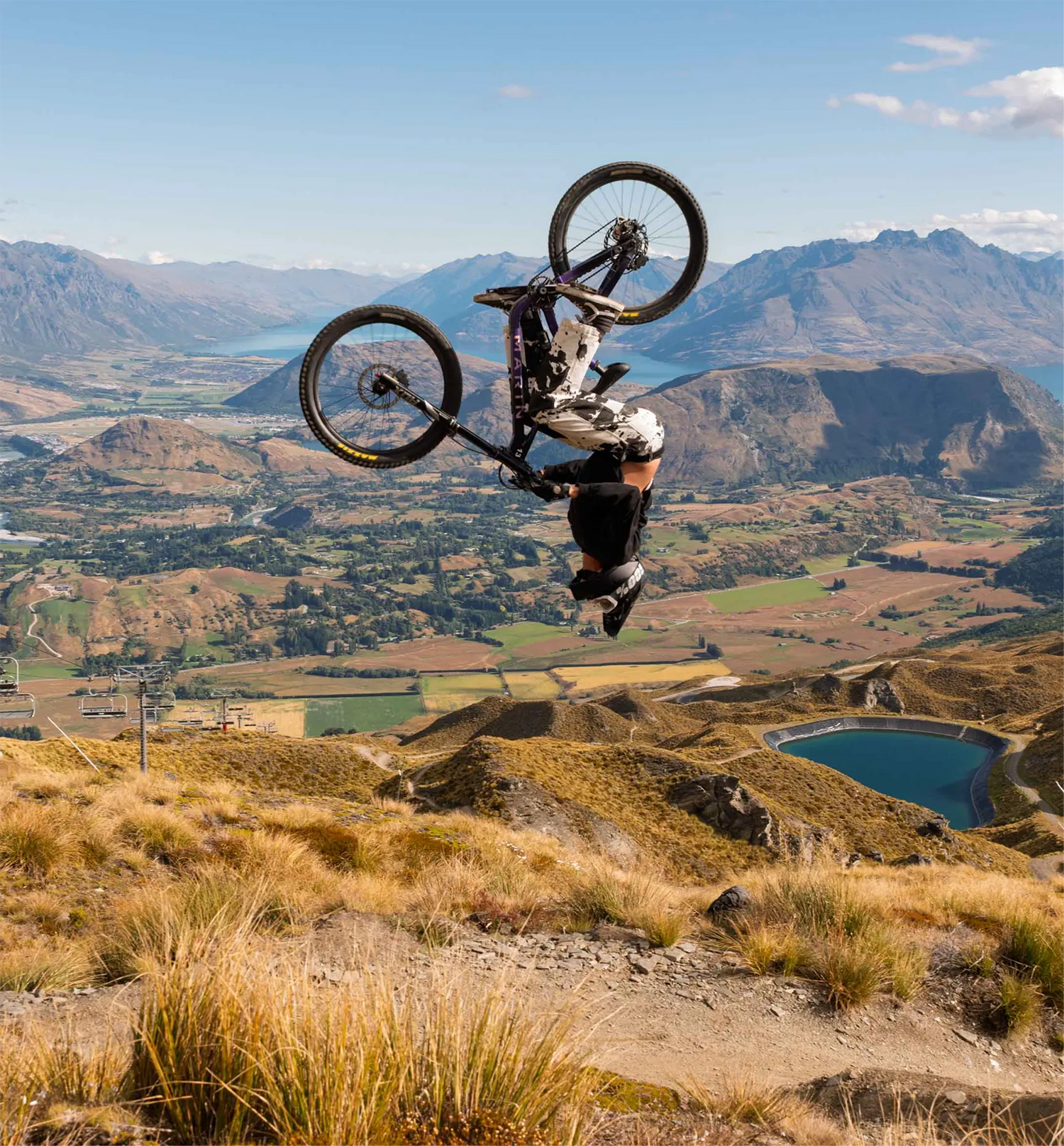 Person on a mountain bike performing a jump with a scenic landscape in the background