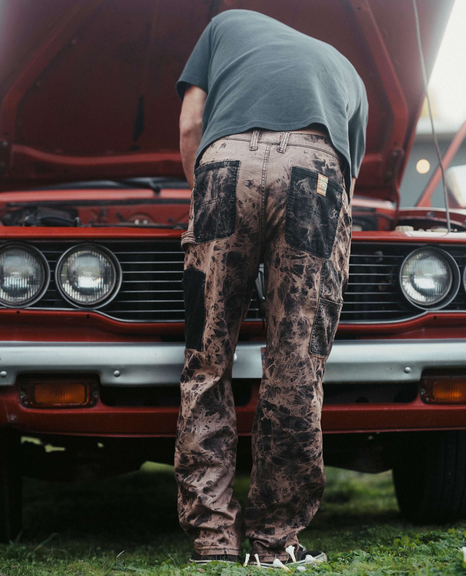 Isaac under the hood of his truck in Mixed Nuts Superlite Utility Jeans