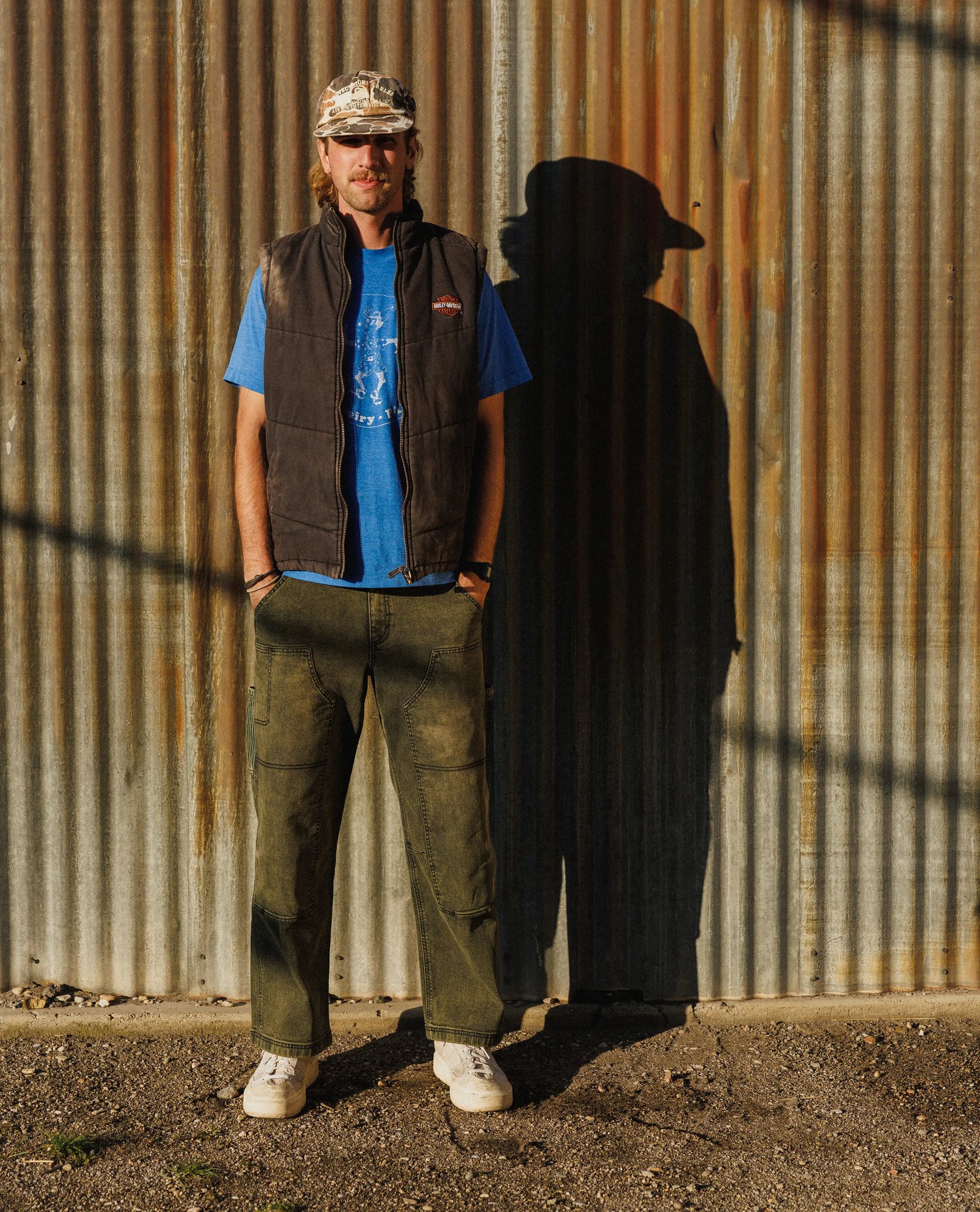 Man standing against a corrugated metal wall casting a shadow