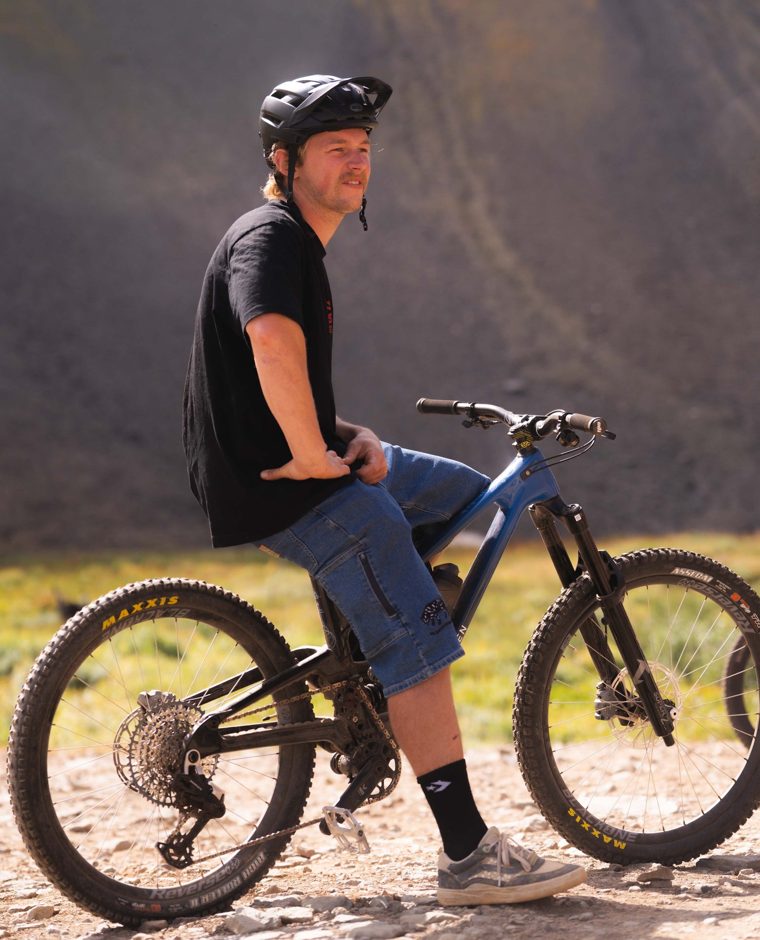 Billy sitting on a mountain bike in a natural setting with mountains in the background
