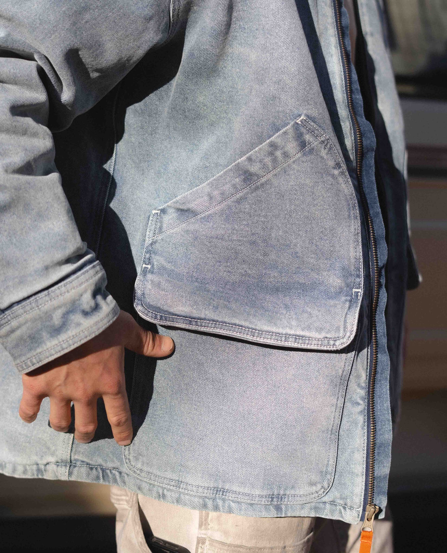 Person wearing a light blue denim jacket with a pocket detail.