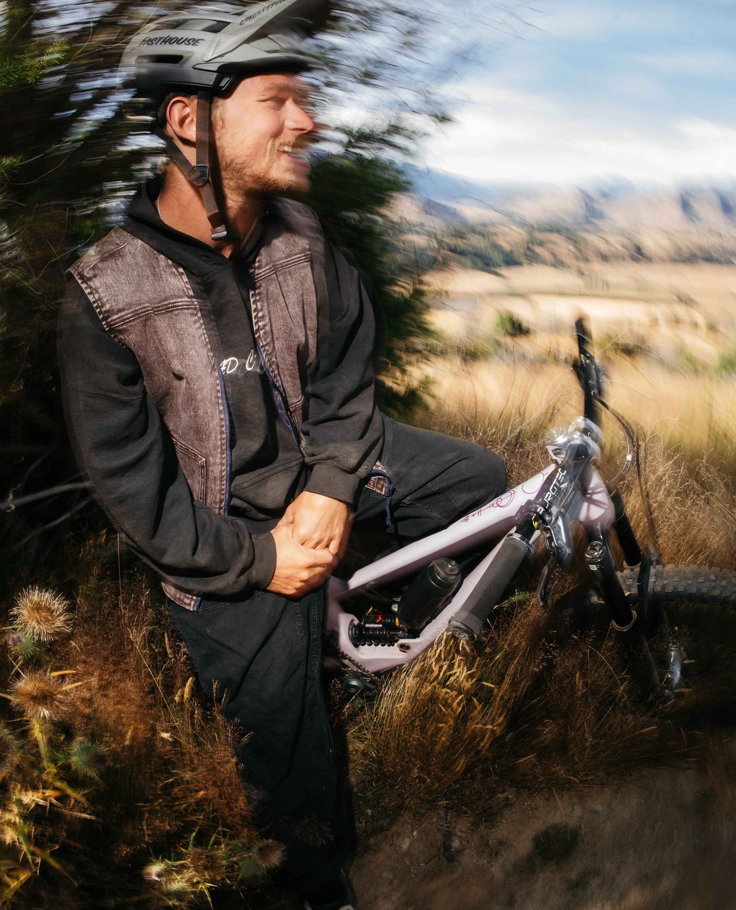 Man sitting on a bike in a natural setting with mountains in the background