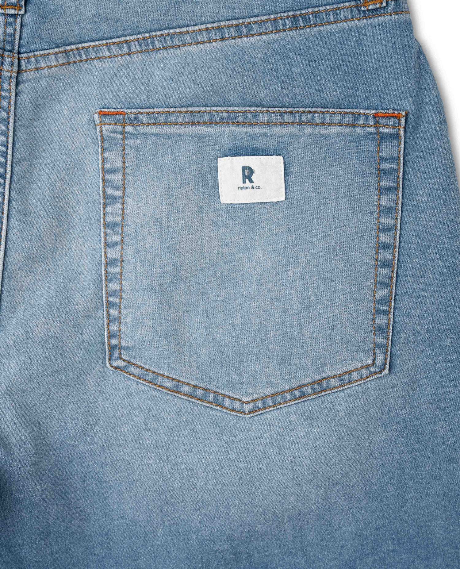 Close-up of a blue denim pocket with a brand label on a white background