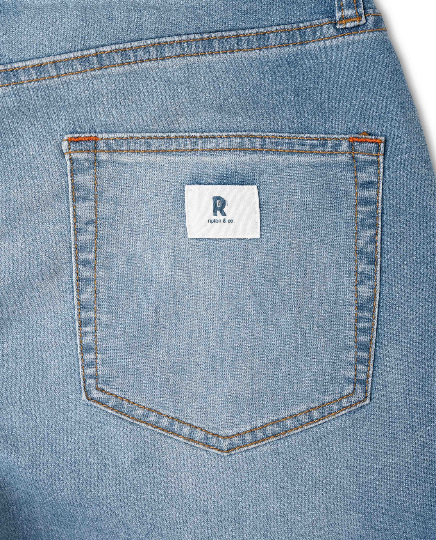 Close-up of a blue denim pocket with a brand label on a white background
