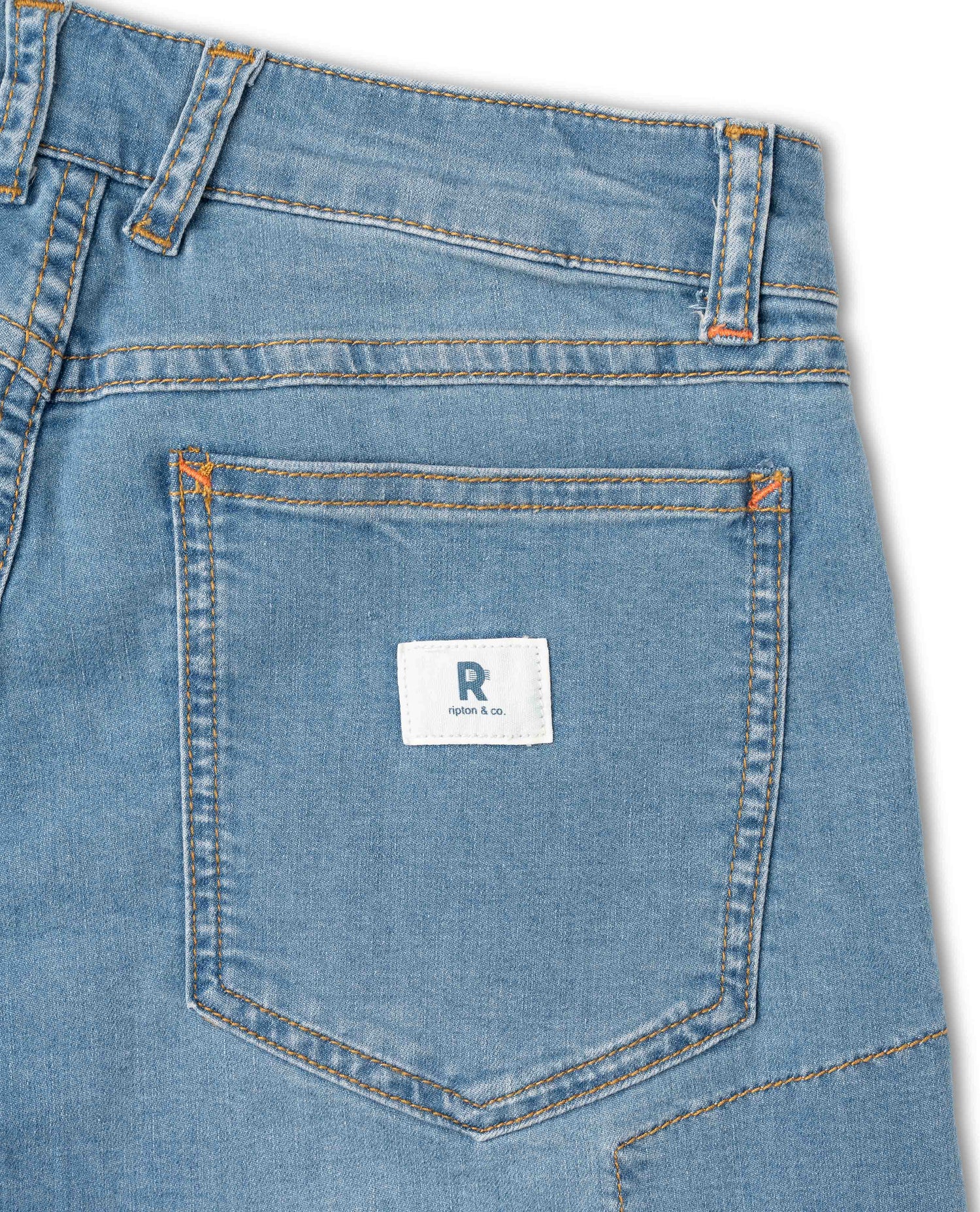 Close-up of a blue denim pocket with a brand logo on a white background