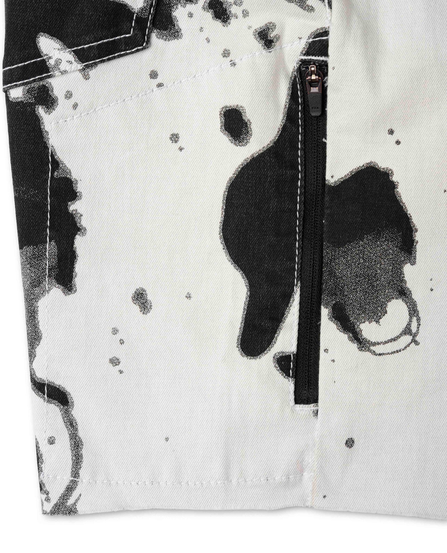 Close-up of a white jacket with black abstract patterns and a zipper.