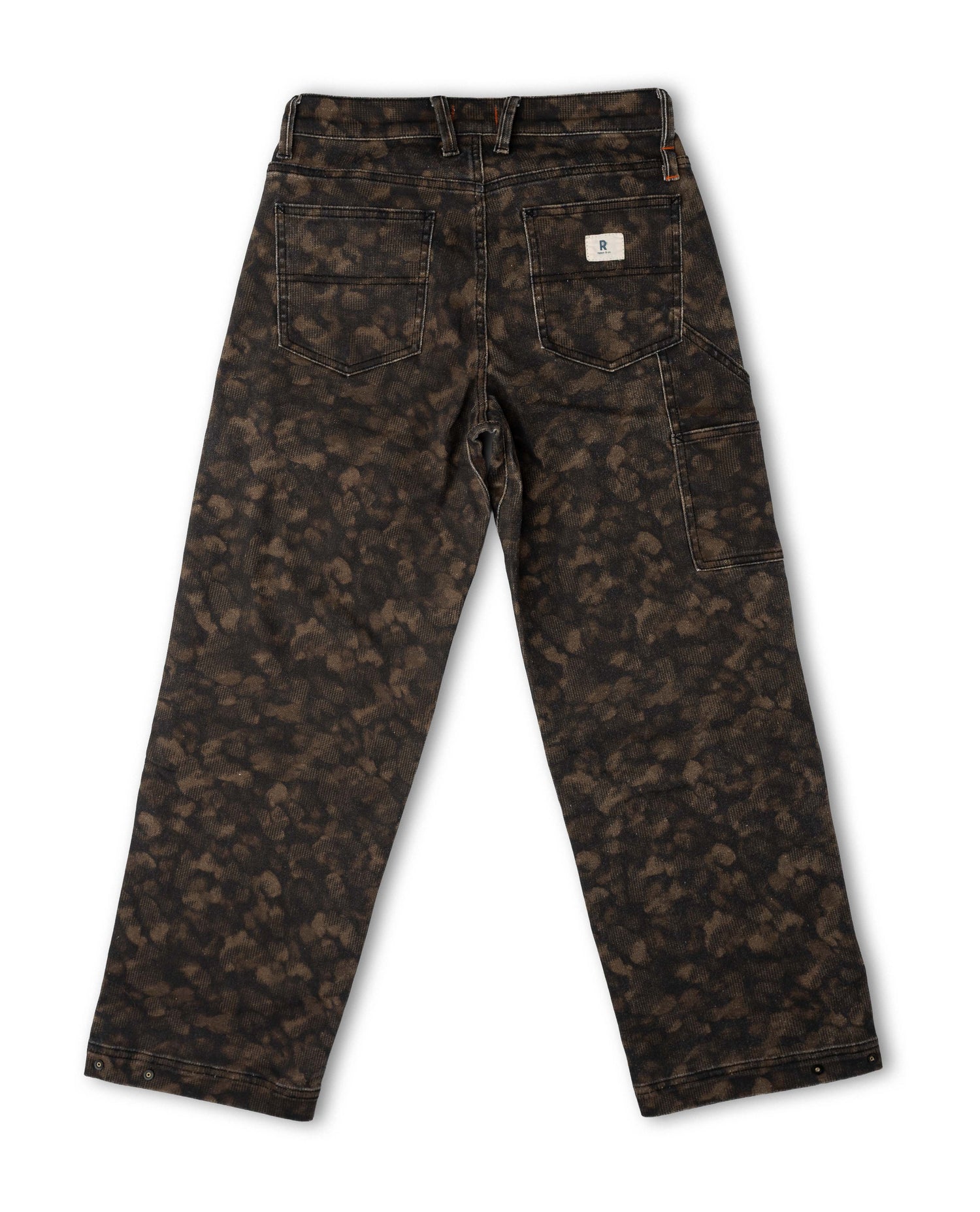 A pair of Carhartt pants shown from the back, featuring a dark brown and black camouflage pattern, a white Carhartt brand patch on the back pocket, and a button closure.