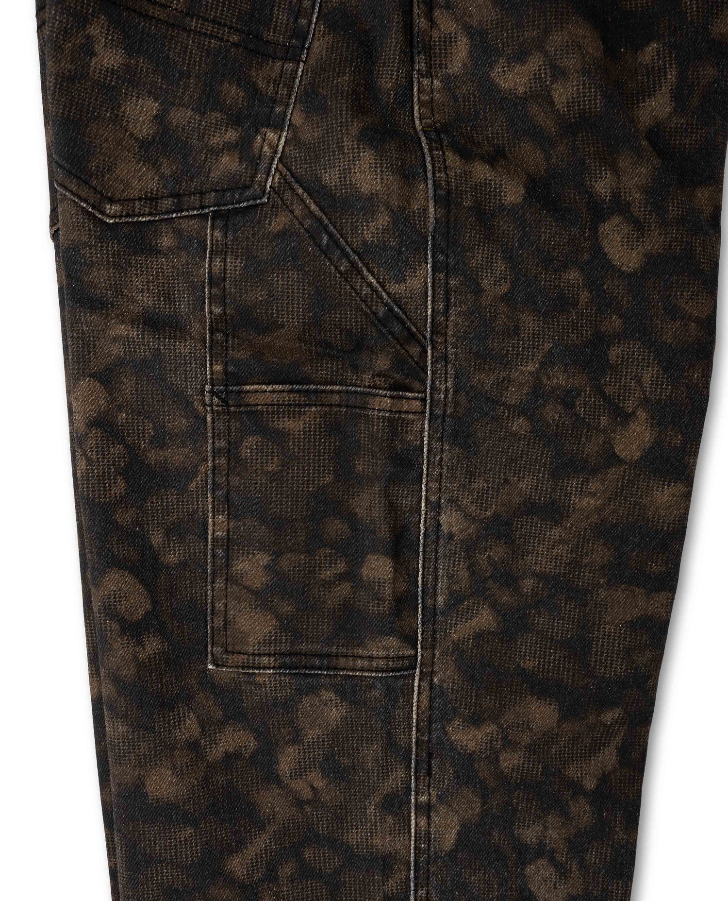 Close-up of dark brown and black mottled patterned fabric on a pair of pants, showing a pocket and stitched seam details against a white background.