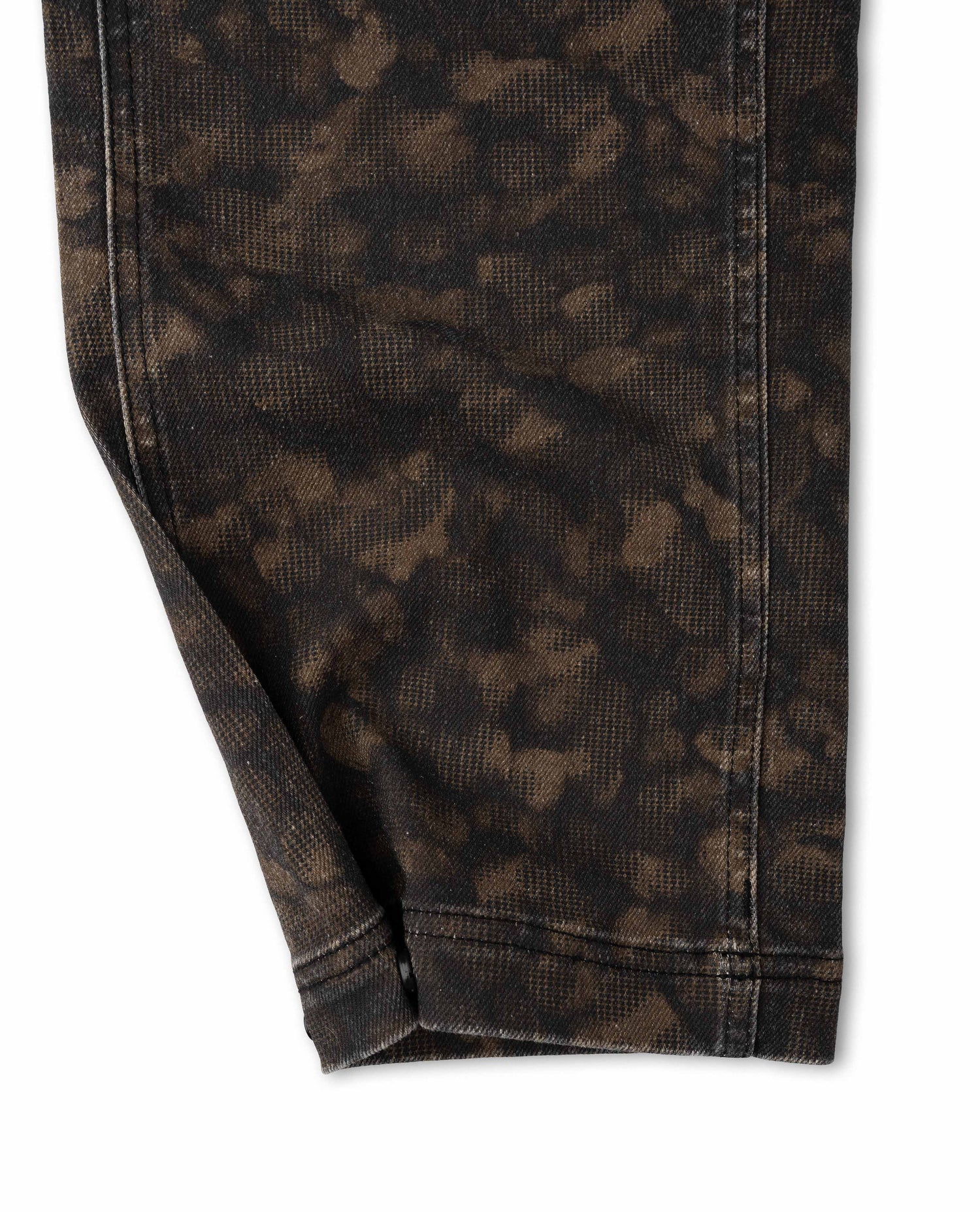 Close-up of a pair of dark brown and black acid-wash or tie-dye jeans showing the fabric texture, seams, and hem on a white background.