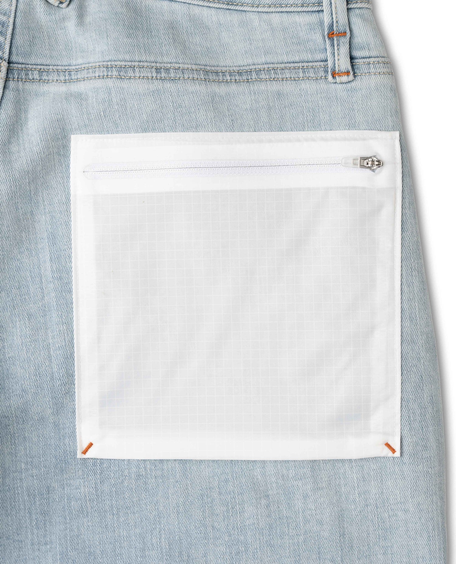 Close-up of a light blue denim pocket with a white patch on a white background