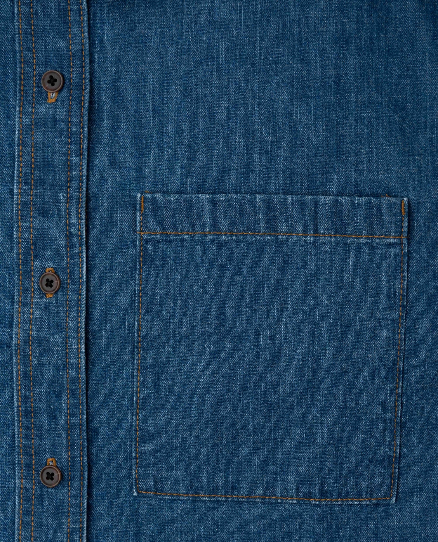 Close-up of a blue denim shirt with a pocket and buttons.