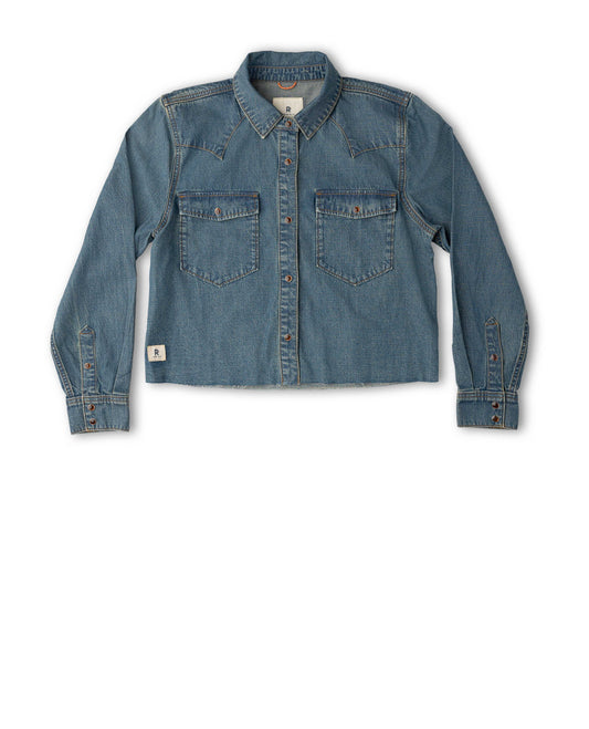 A cropped blue denim shirt jacket with long sleeves, button-down front, and two chest flap pockets, shown flat against a plain white background.