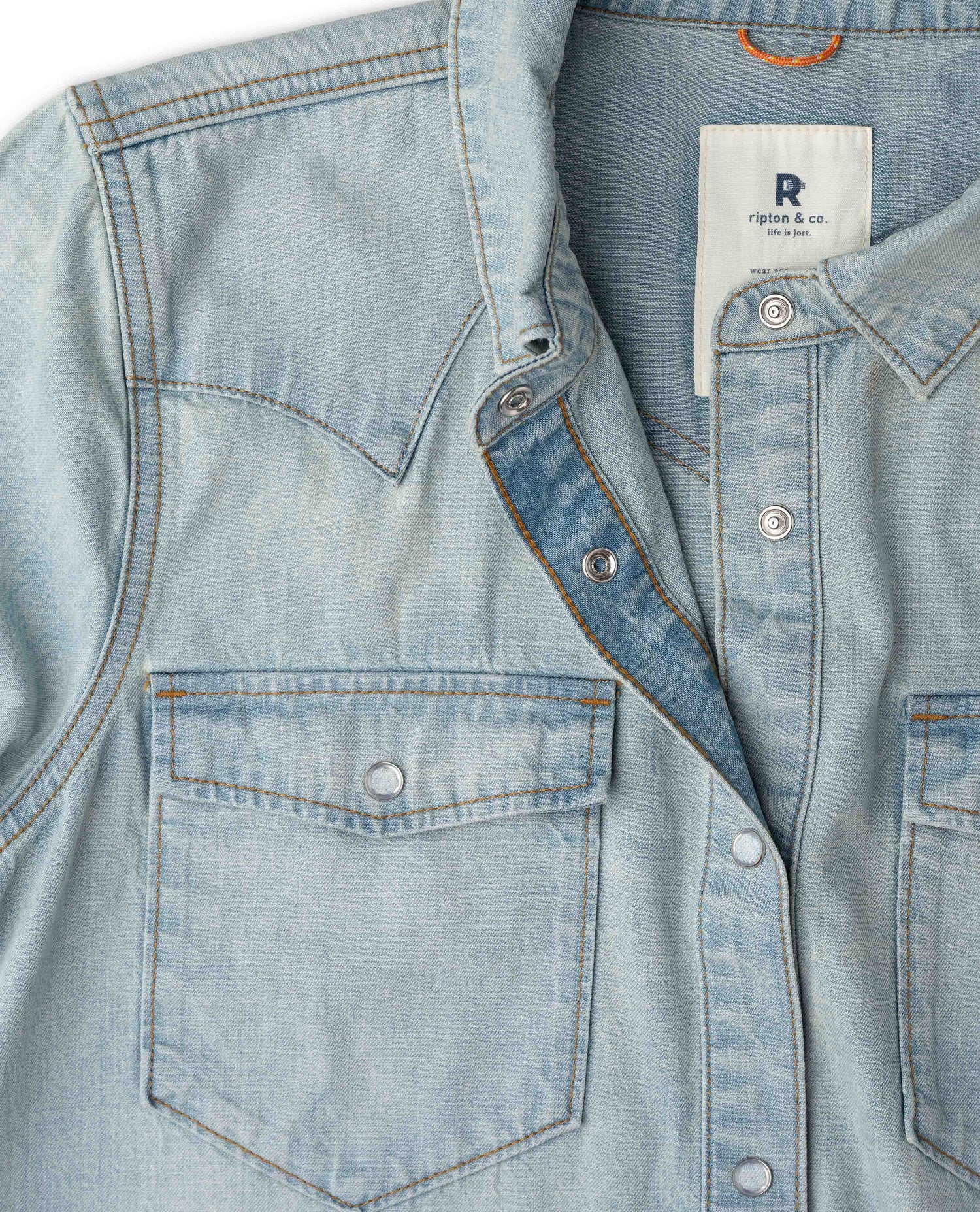 Close-up of a light blue denim western-style shirt jacket with chest pockets.