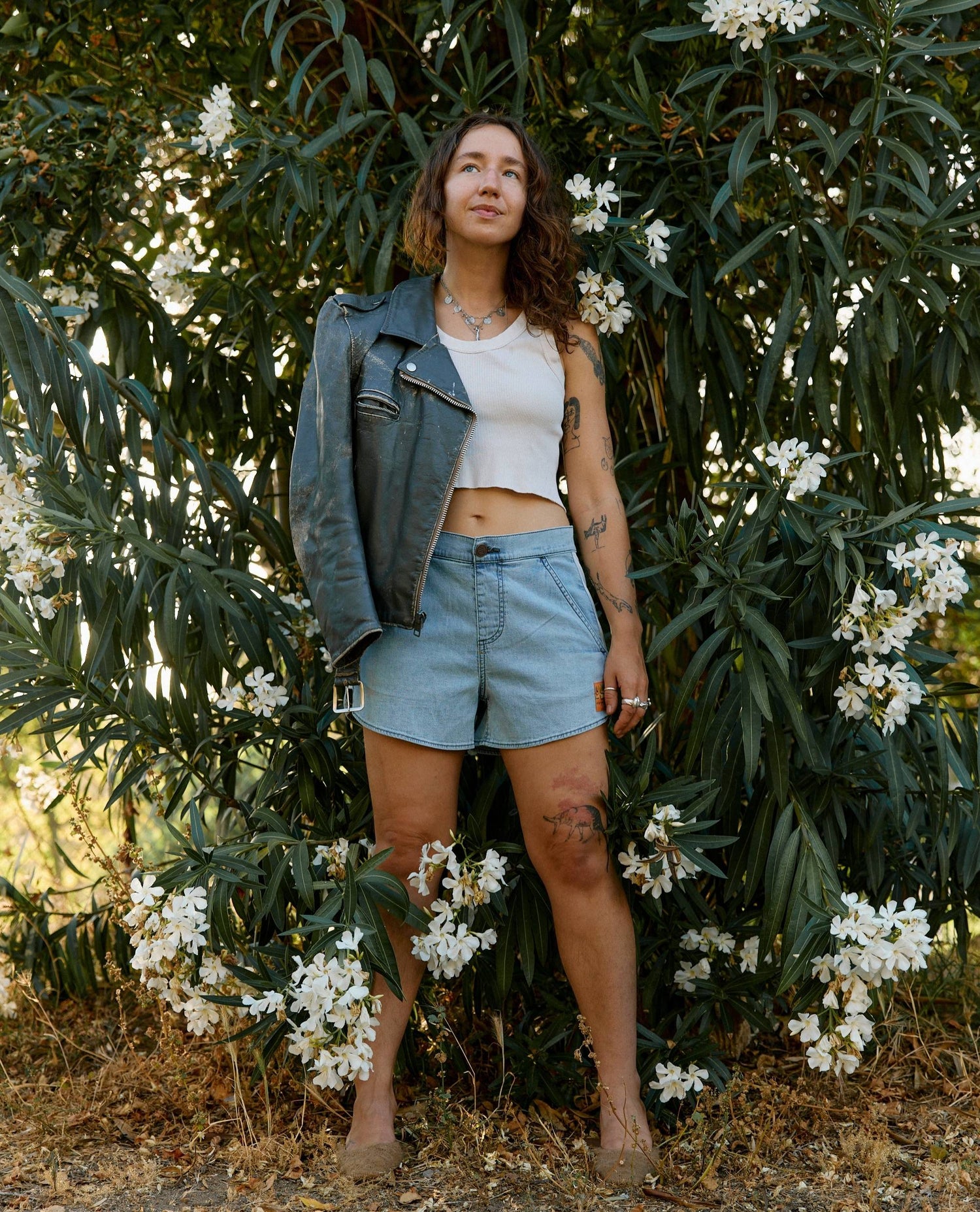 Woman standing among white flowers and green foliage