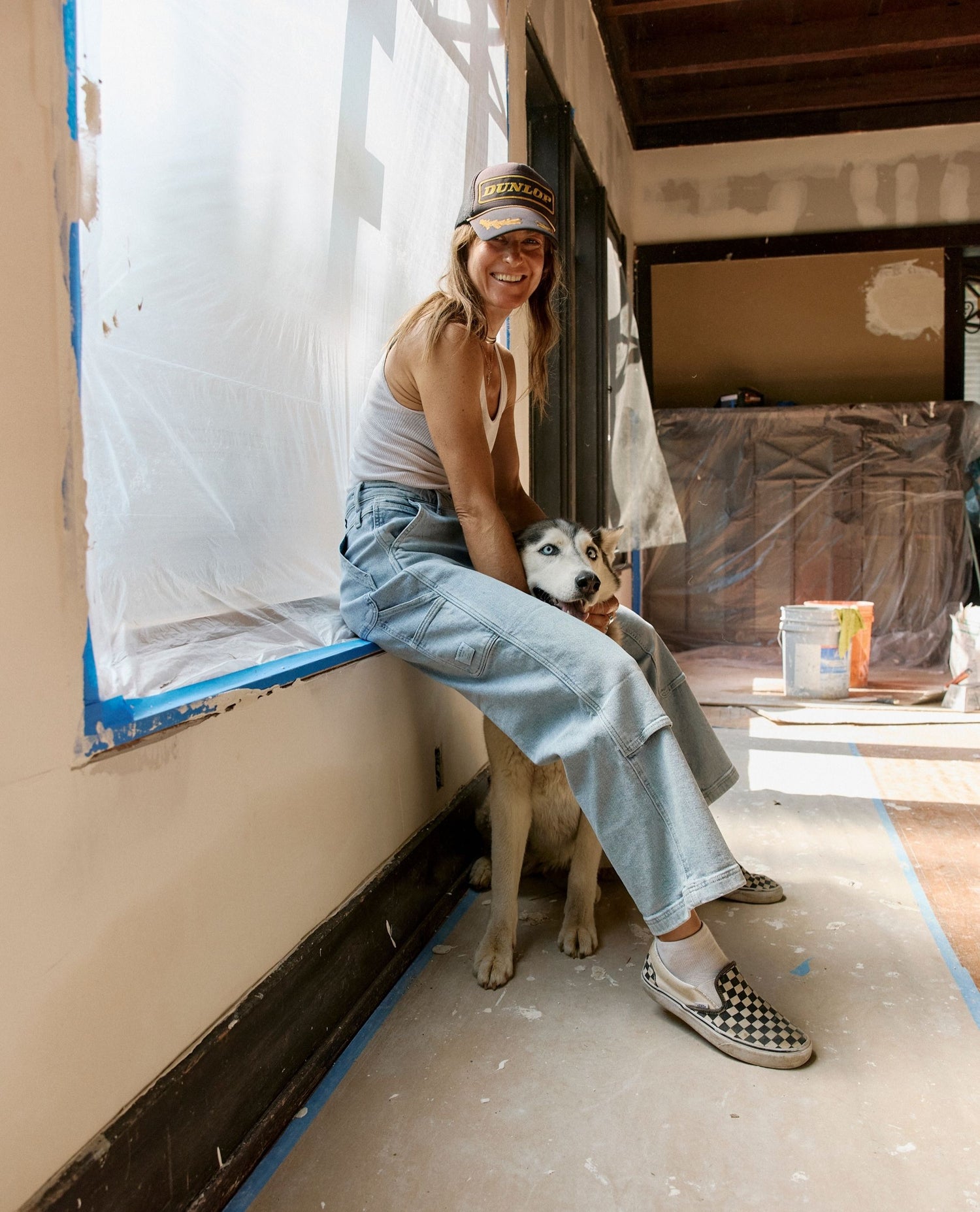 Woman sitting on a floor with a dog, surrounded by construction materials.