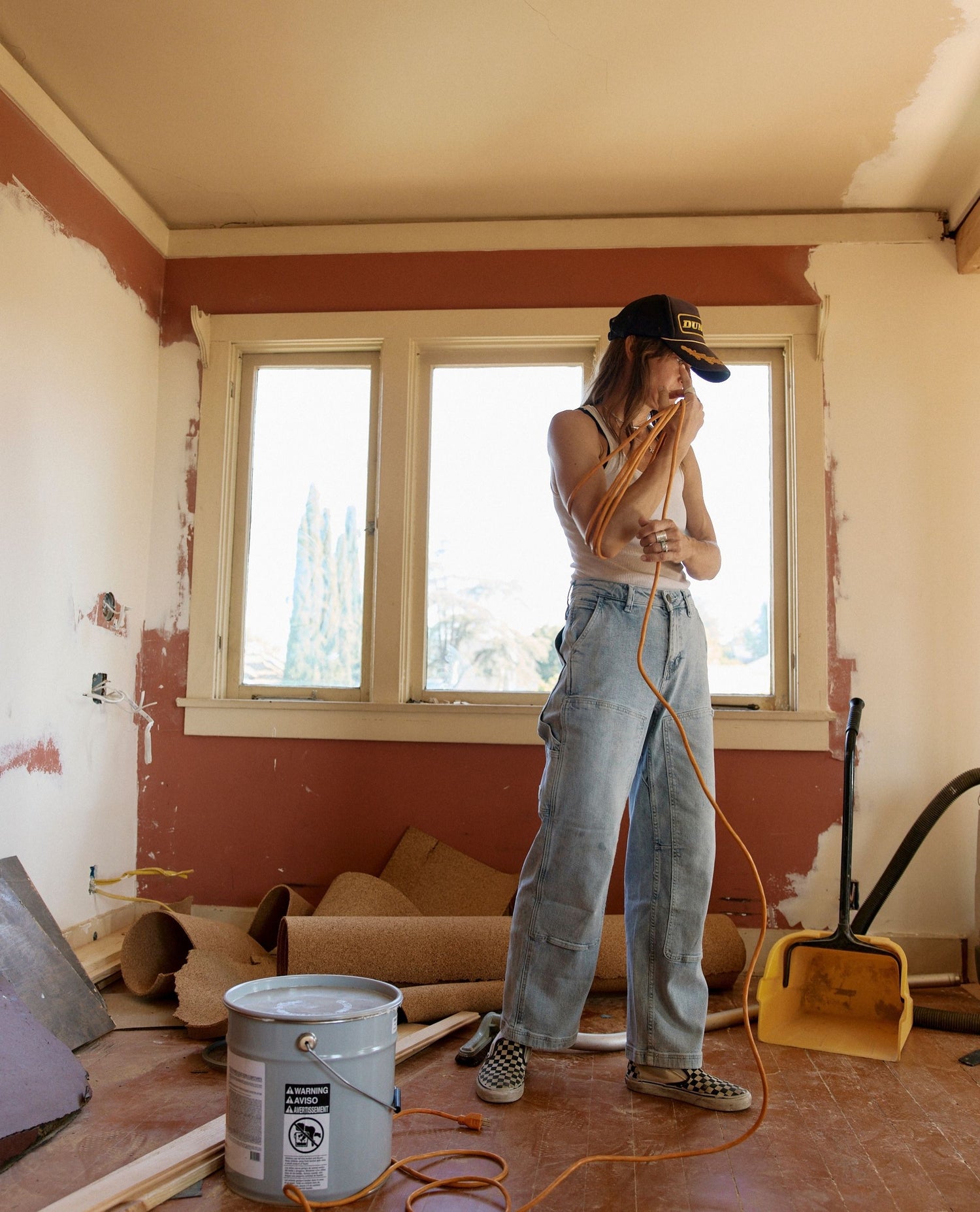 Person cleaning a room with a vacuum cleaner amidst renovation work.