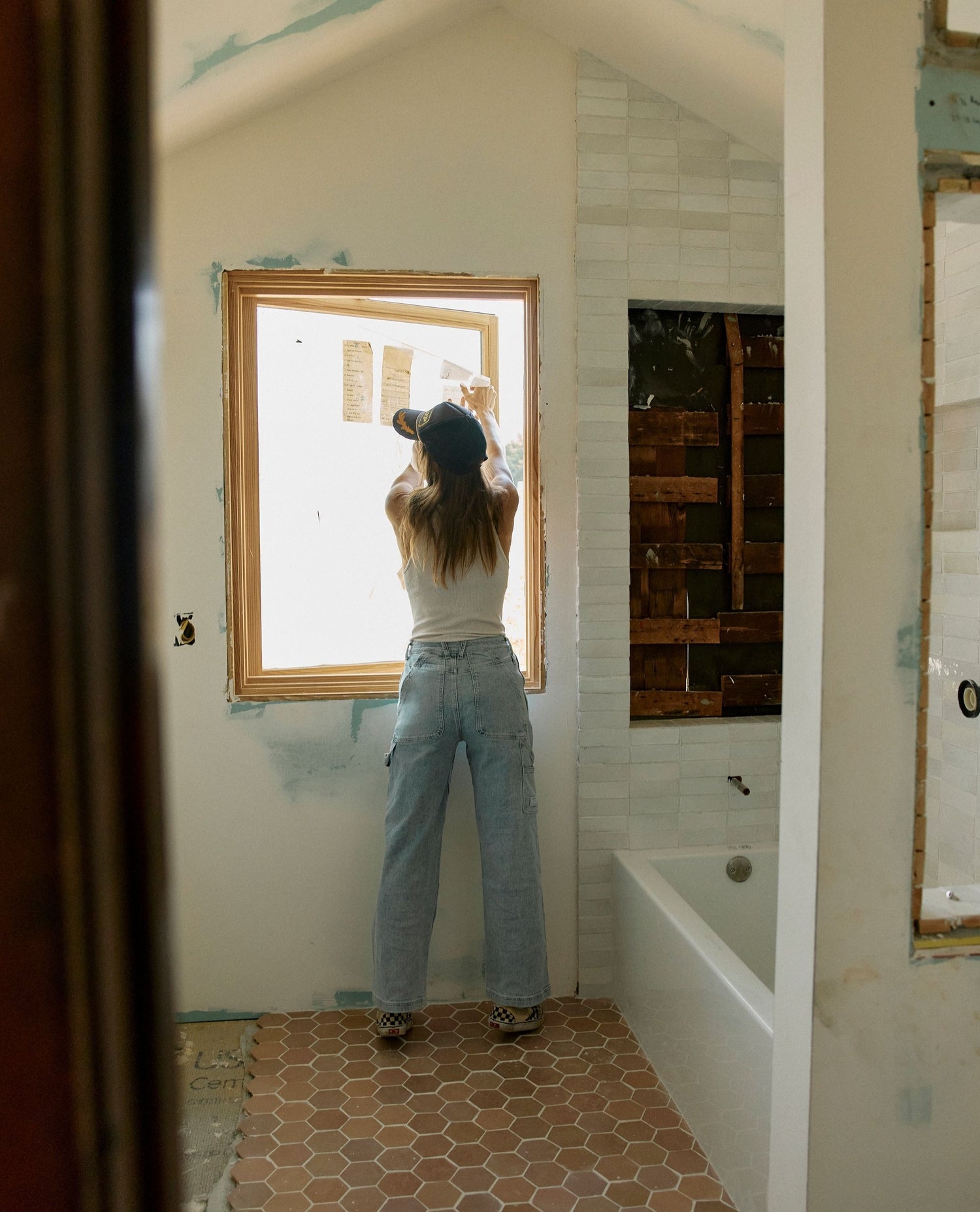 Person installing a window in a bathroom under construction