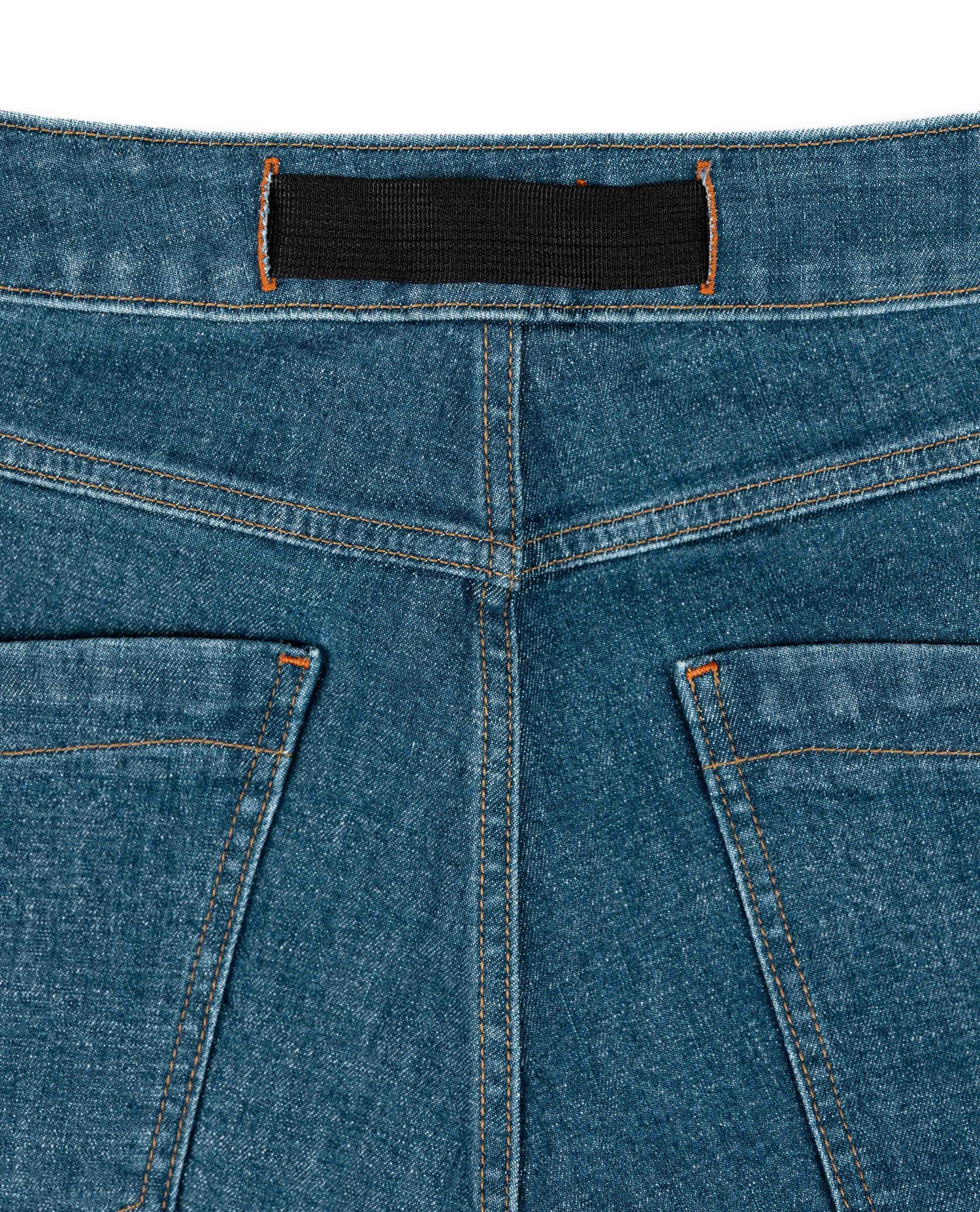 Close-up of blue denim jeans with a black label on a white background
