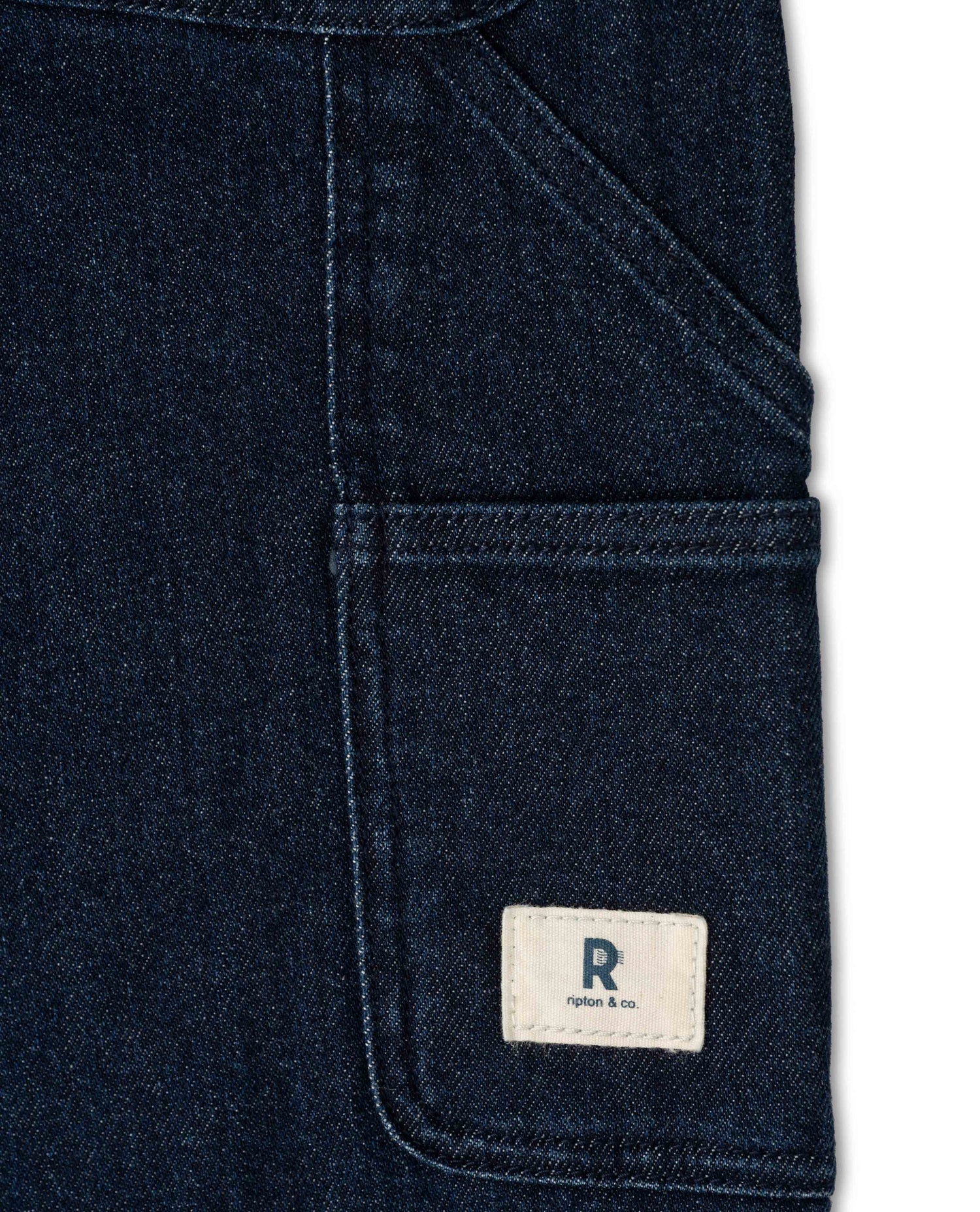 Close-up of a dark blue denim pocket with a brand logo on a white background